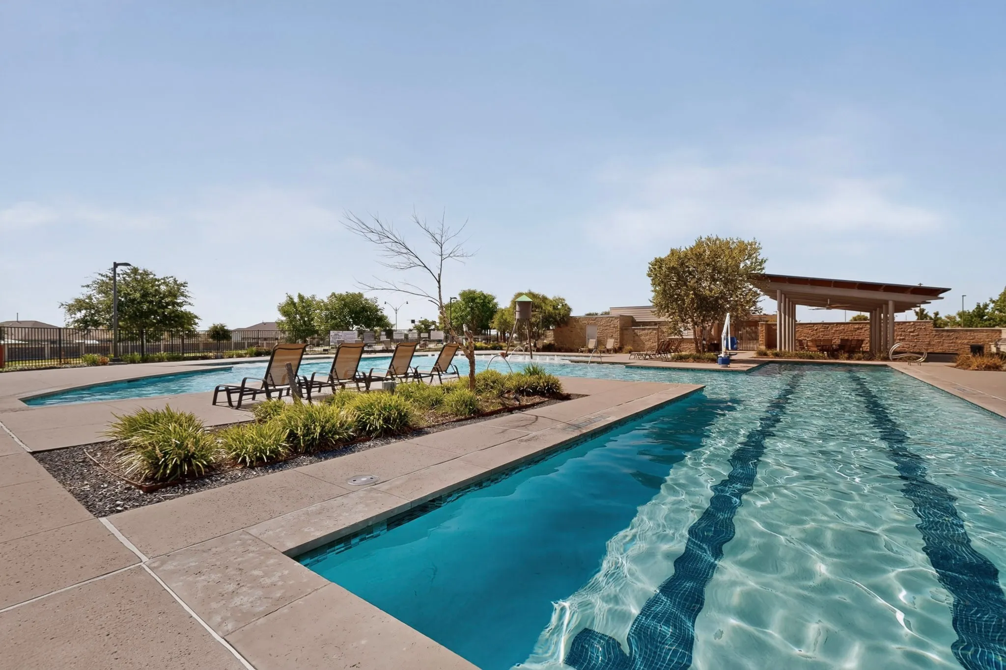 Outdoor swimming facility featuring multiple pools, a covered lounge area, and integrated landscaping