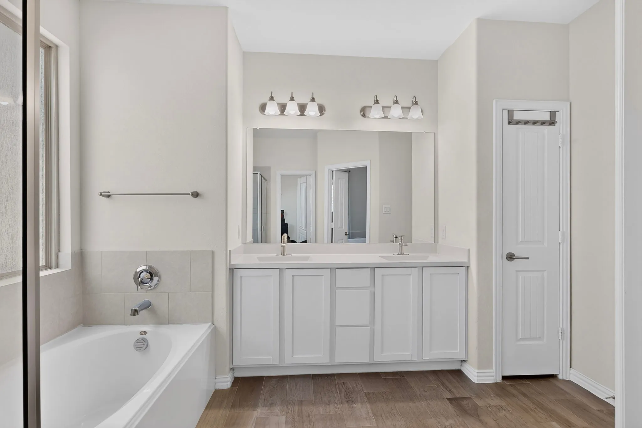 Bathroom featuring a double vanity with white cabinetry and a full-width mirror