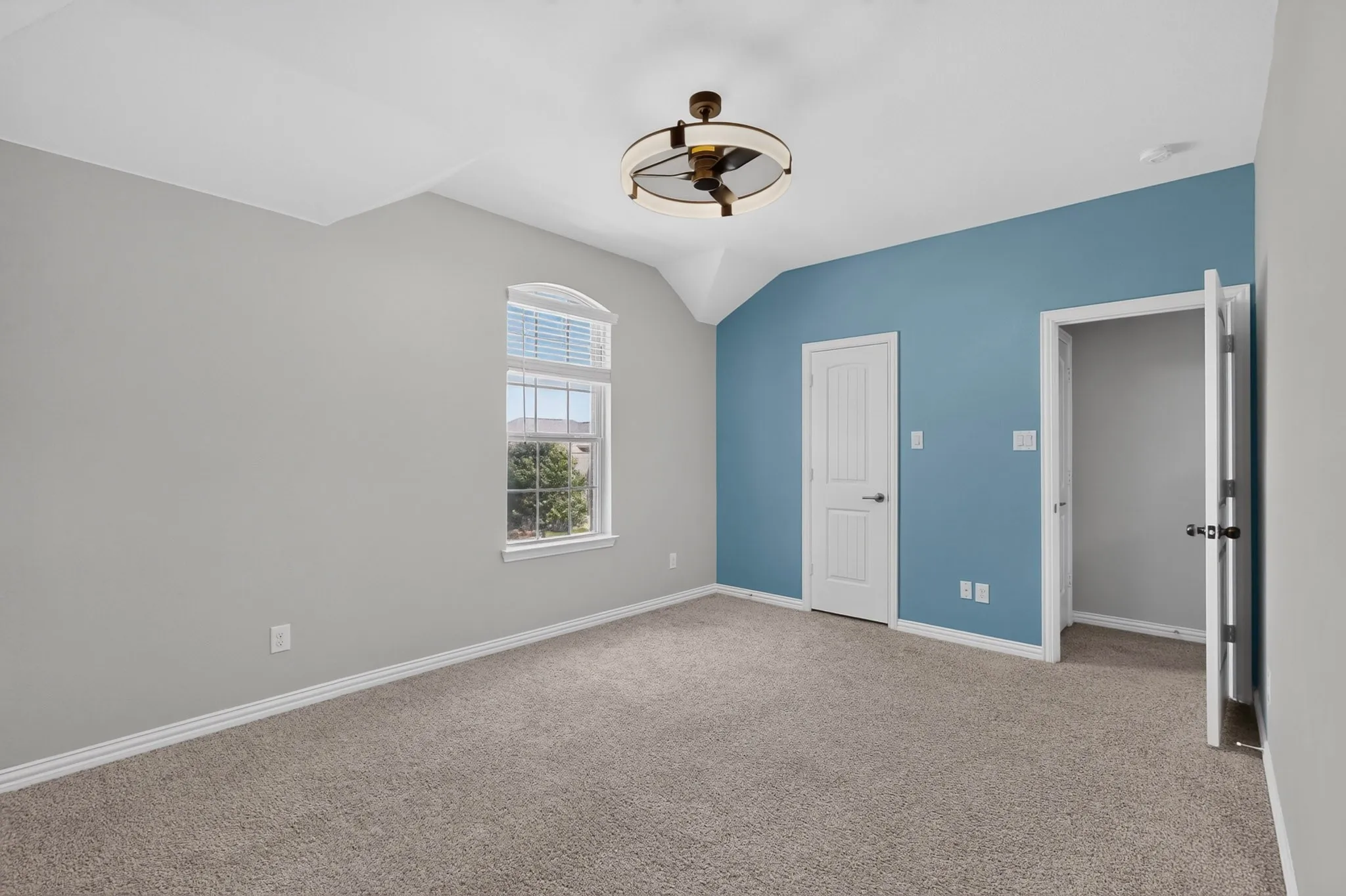 Carpeted room with vaulted ceiling and a decorative ceiling fan