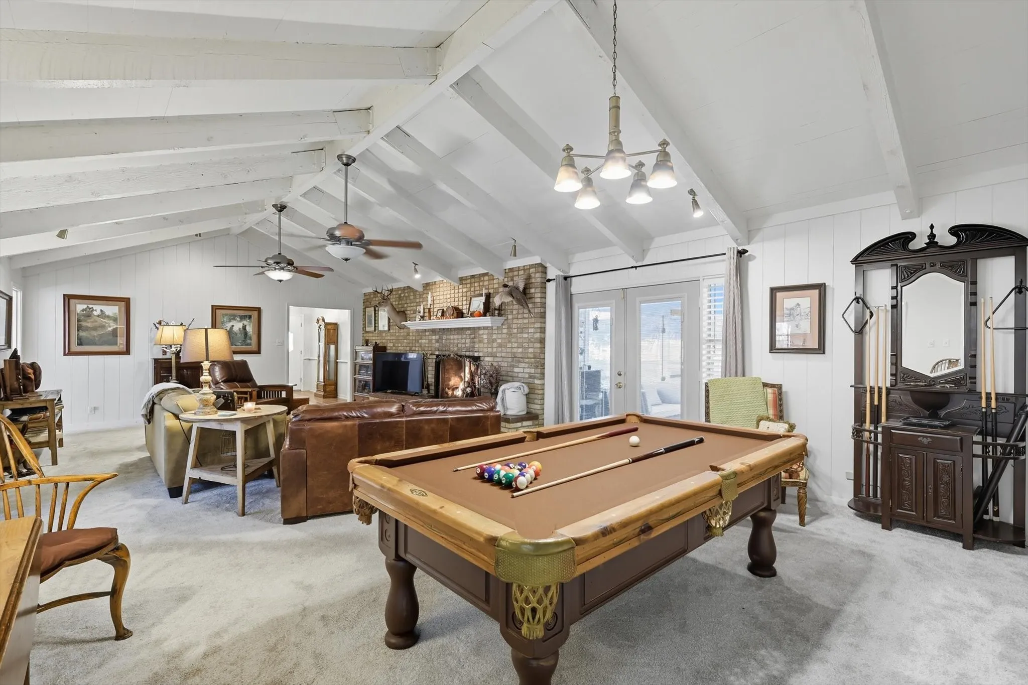 Living room with pool table, french doors, a brick fireplace, pool table, carpet, and wood walls