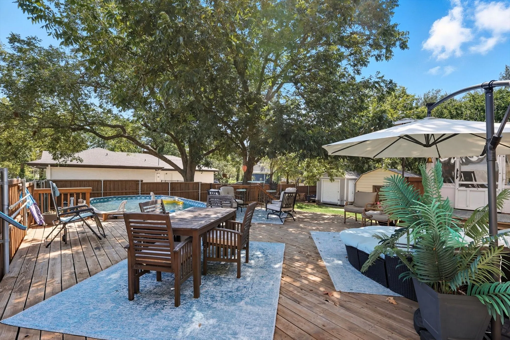 Wooden terrace with a storage unit, a fenced backyard, and outdoor dining space