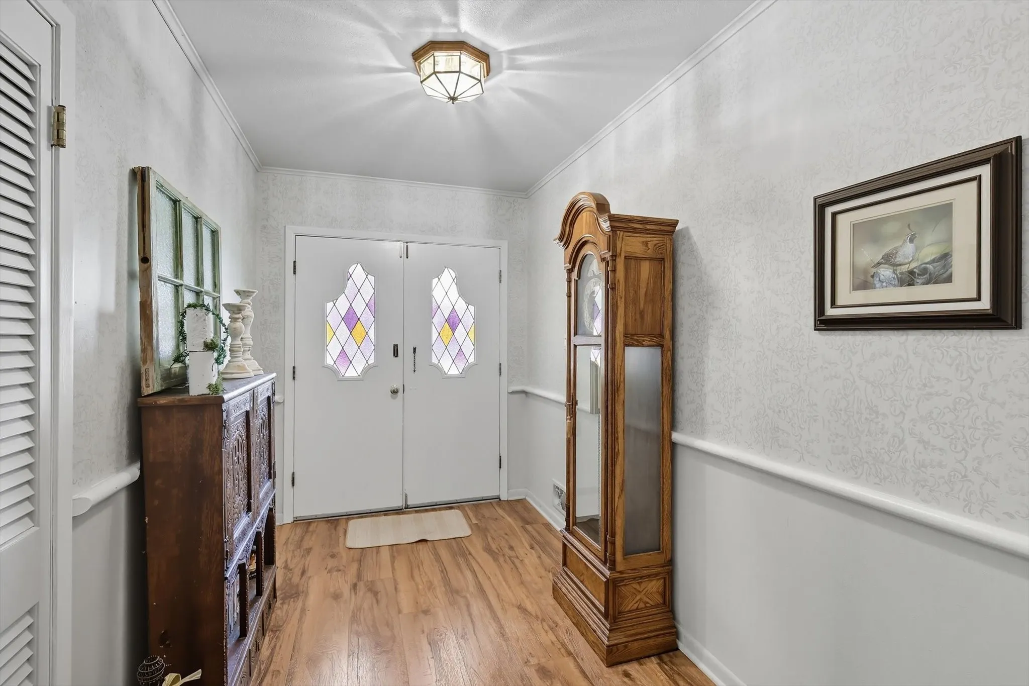 Entrance foyer featuring ornamental molding and light wood-style flooring