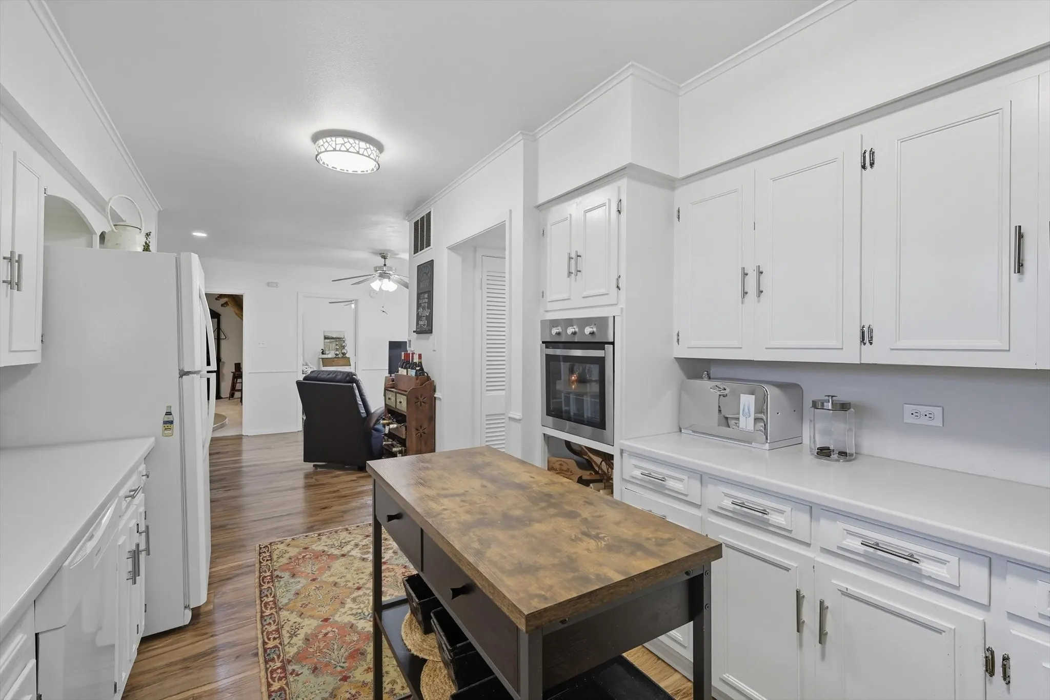 Kitchen featuring light countertops, white cabinetry, light wood-style floors, white appliances, and ceiling fan
