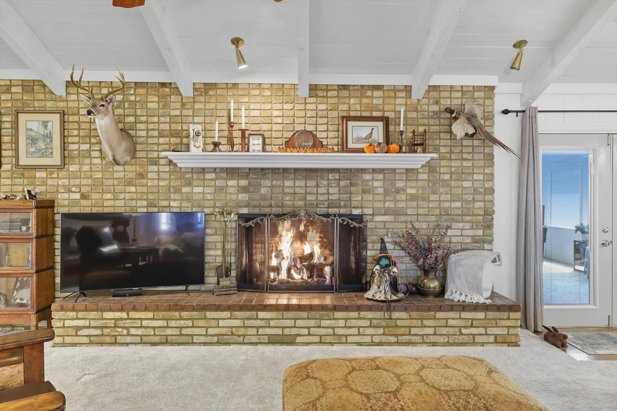 Detailed view of carpet flooring, beamed ceiling, and a brick fireplace