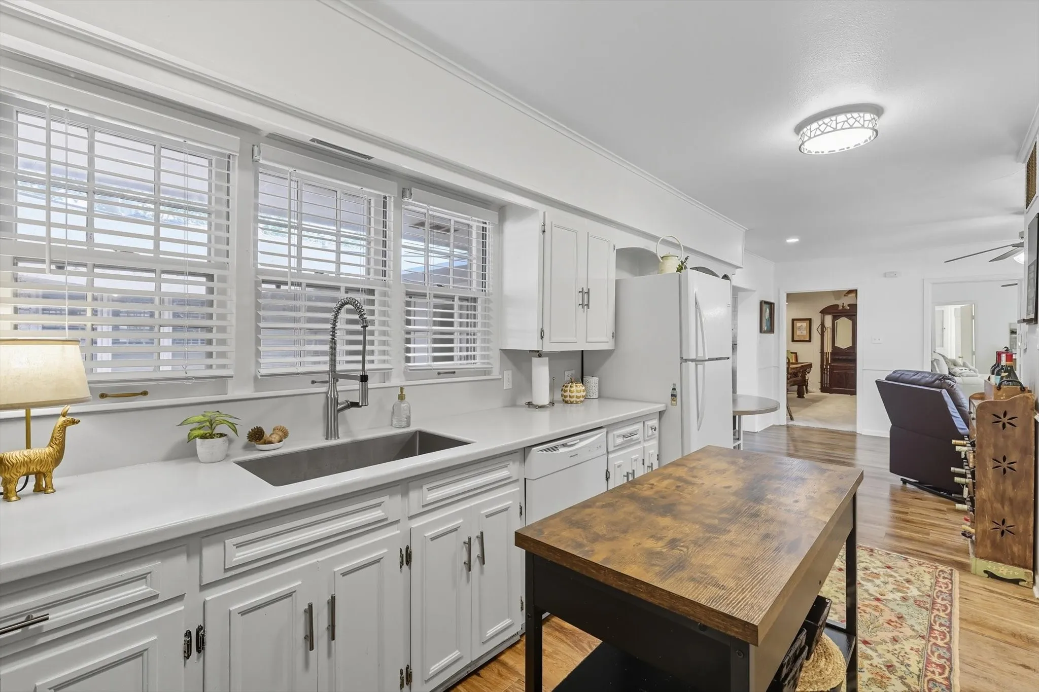 Kitchen with white cabinets, light wood-style flooring, a ceiling fan, white appliances, and ornamental molding