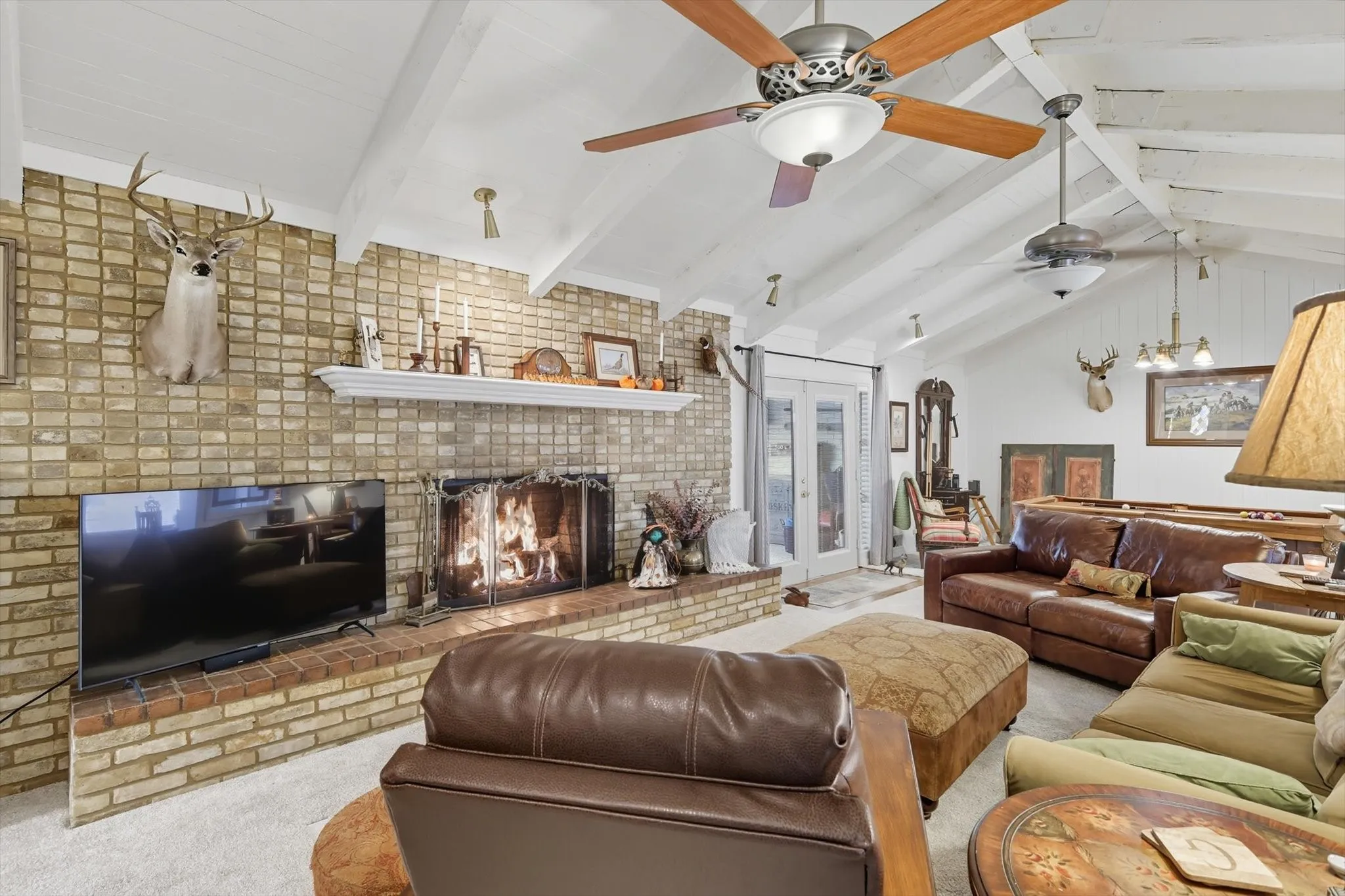 Carpeted living area featuring a brick fireplace and french doors