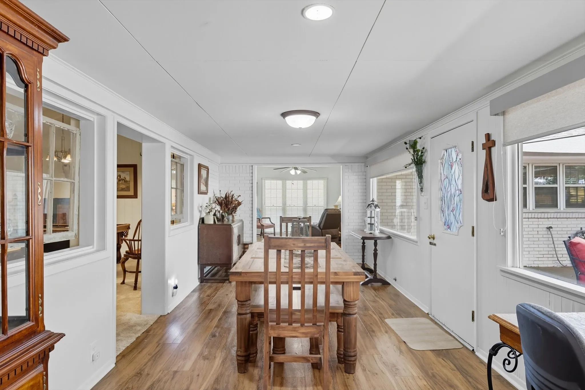 Dining space featuring wood finished floors, ceiling fan, and brick wall
