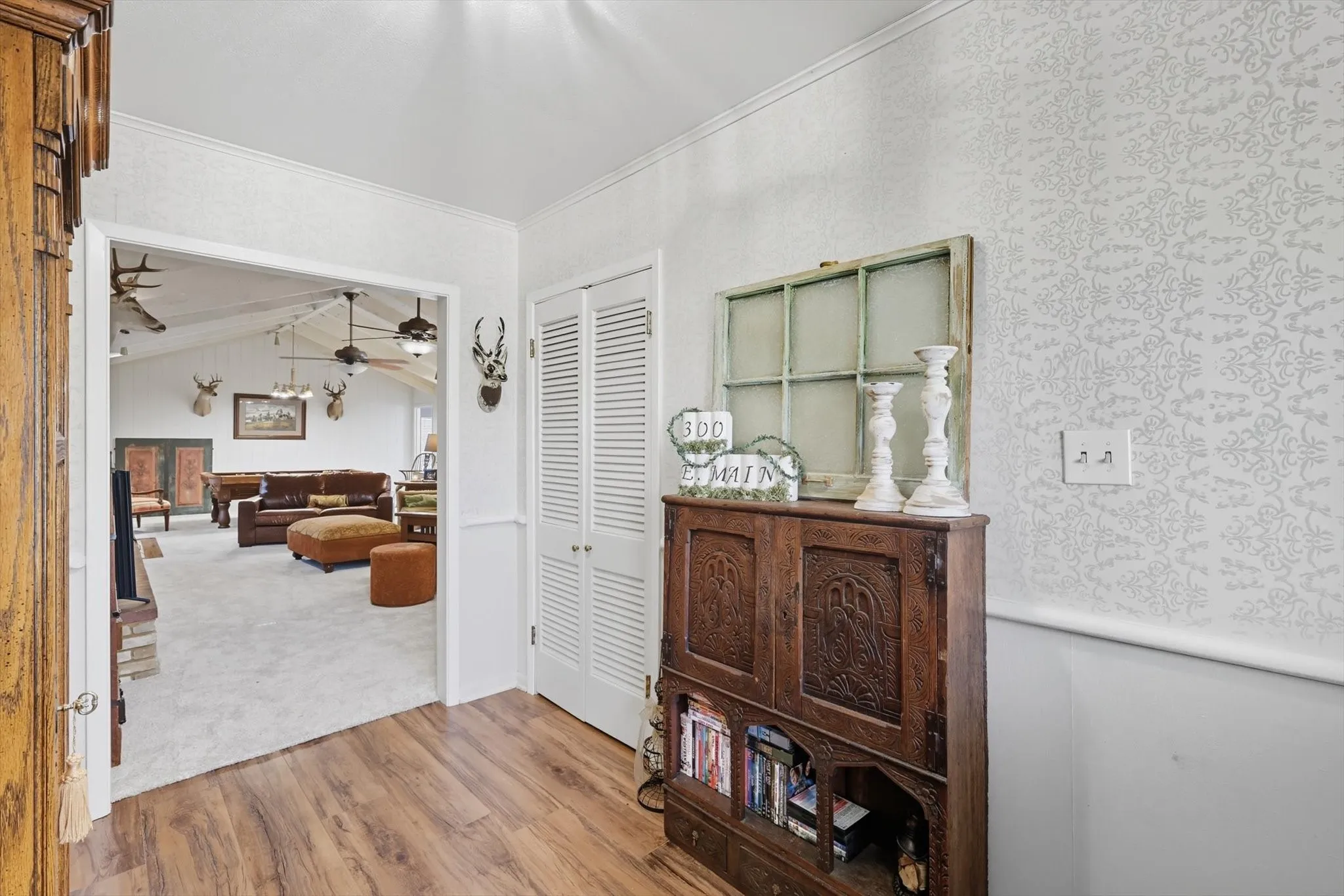 Hall with wood finished floors, vaulted ceiling, ornamental molding, and carpet