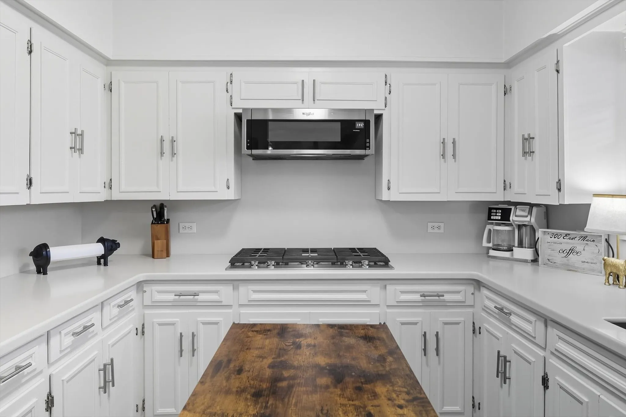 Kitchen featuring white cabinetry and appliances with stainless steel finishes