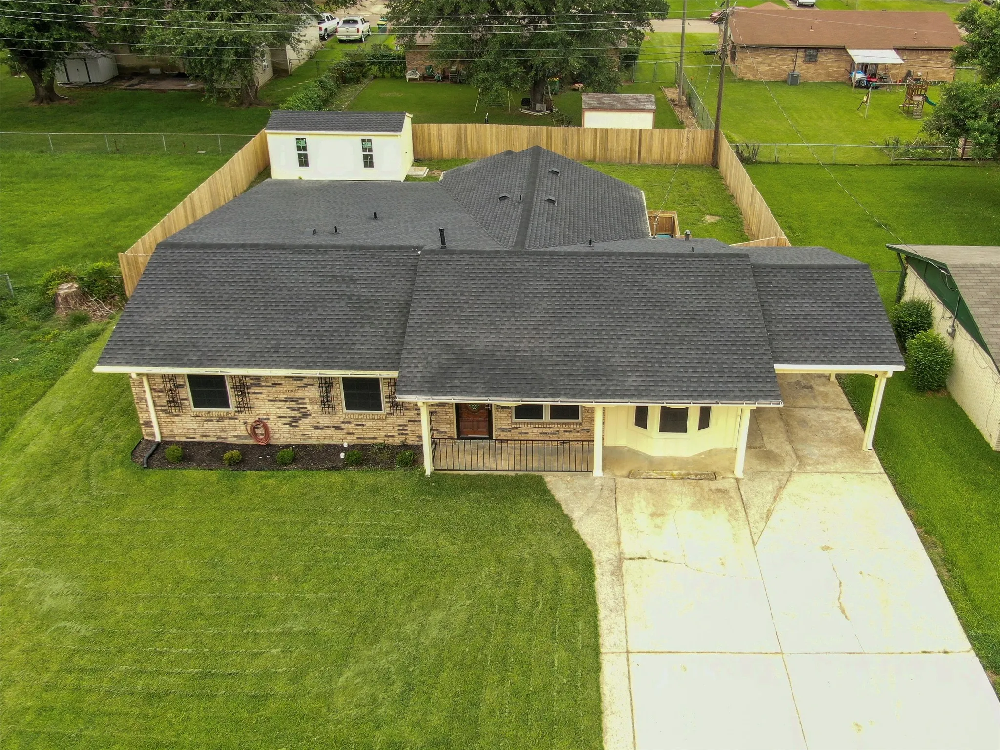 Aerial view of a brick residence with a dark shingle roof