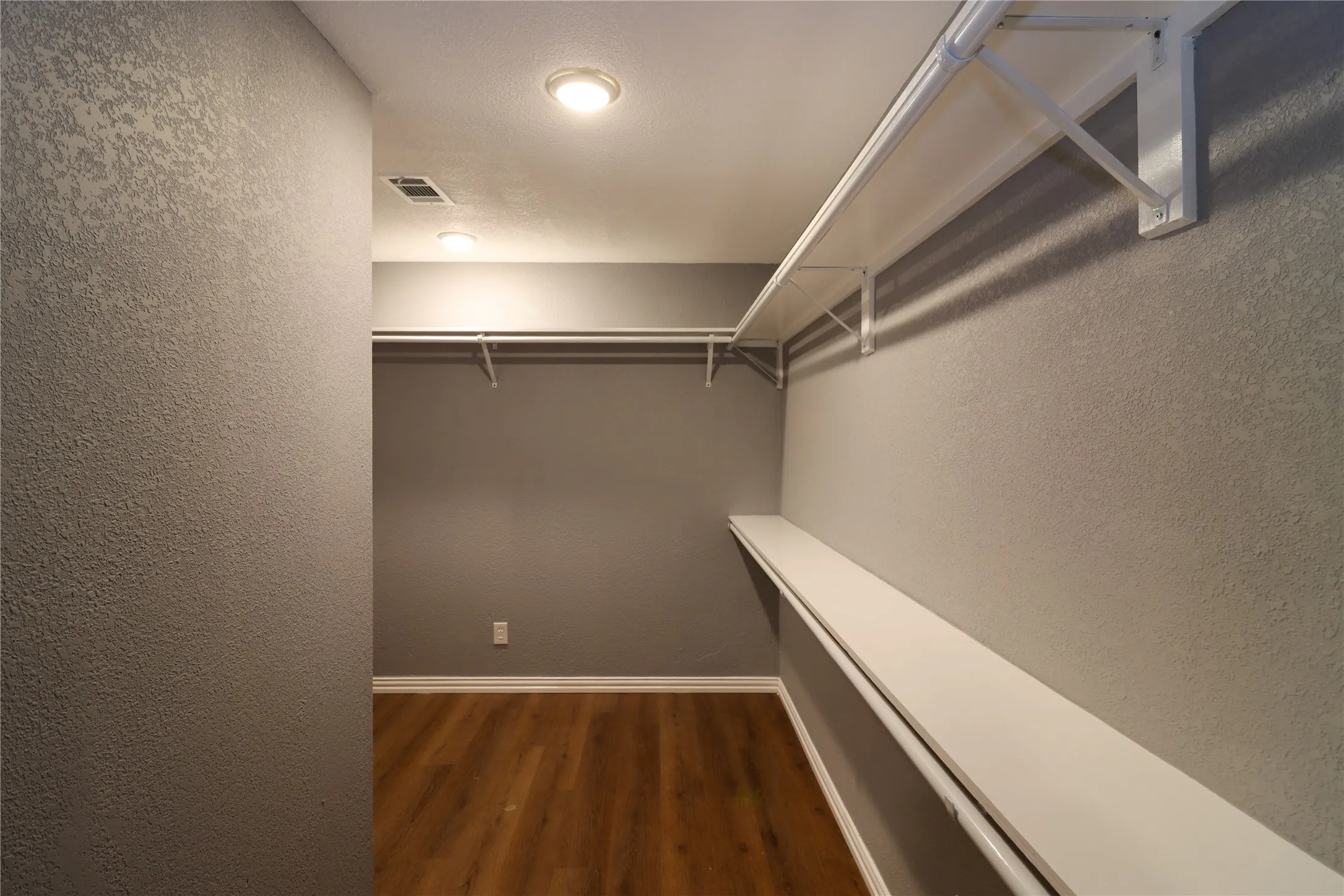 Walk-in closet featuring wood-finish flooring, recessed lighting, and white shelving with hanging rods