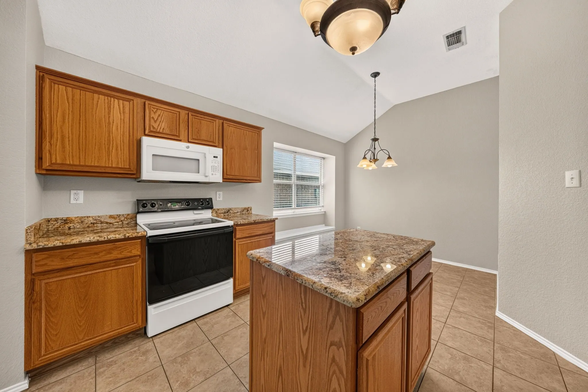 Kitchen with wood-finish cabinetry, granite countertops, and a central island