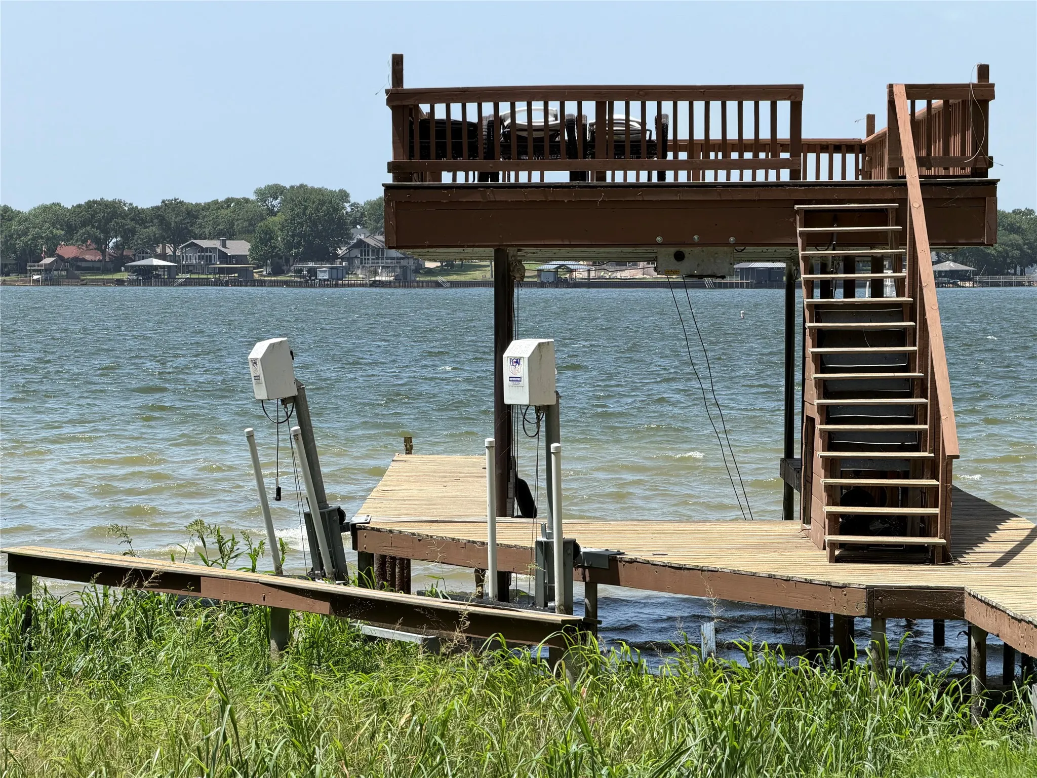 Waterfront dock featuring two PWC boat lifts, upper and lower -level decks, and a boat lift