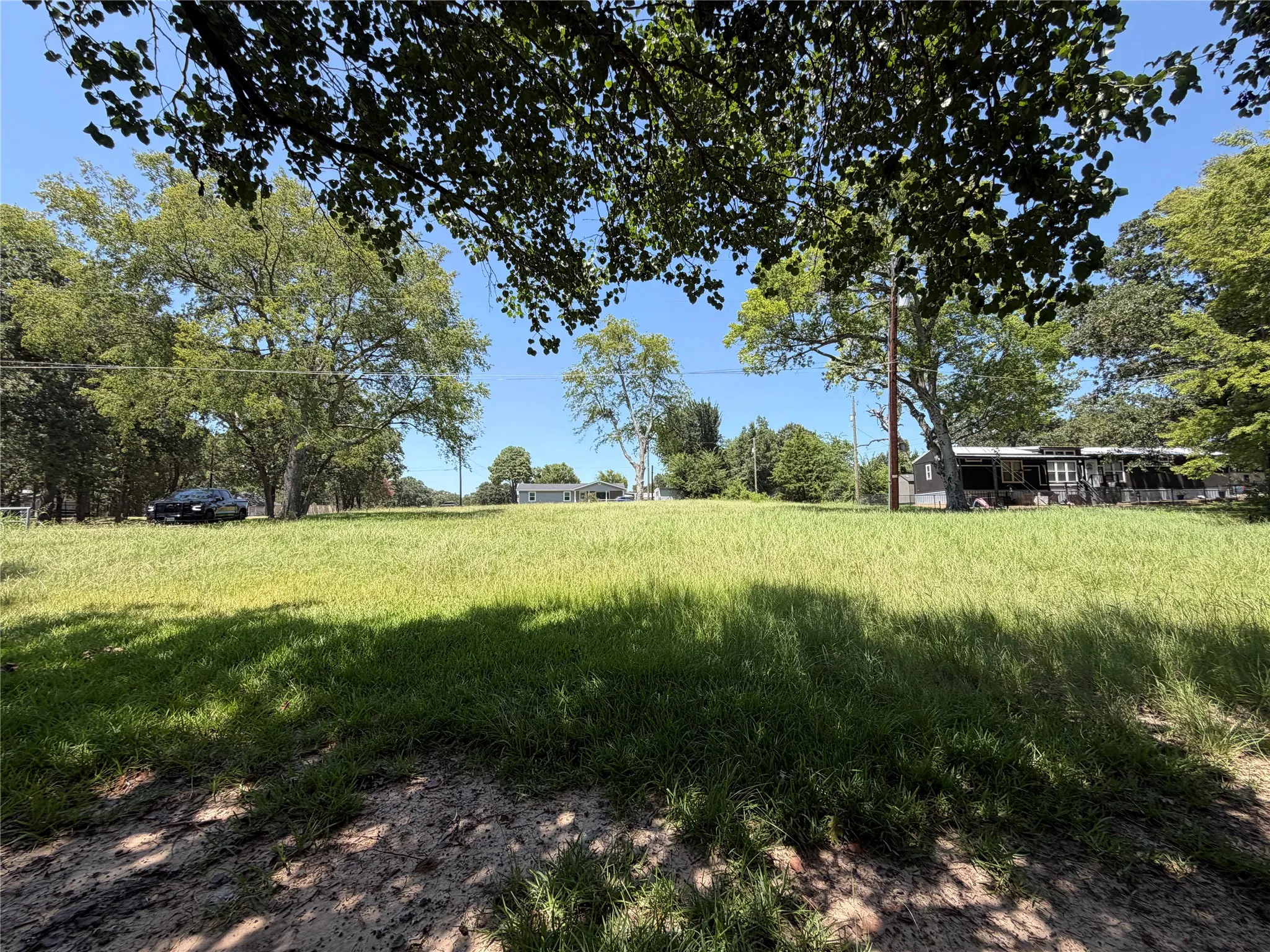 Land view looking from the hedges back at the north end of the land (gray house in background is neighbor at north property line.  Black house on the right is neighbor at the east property line.  Black car is on Scenic Dr.)