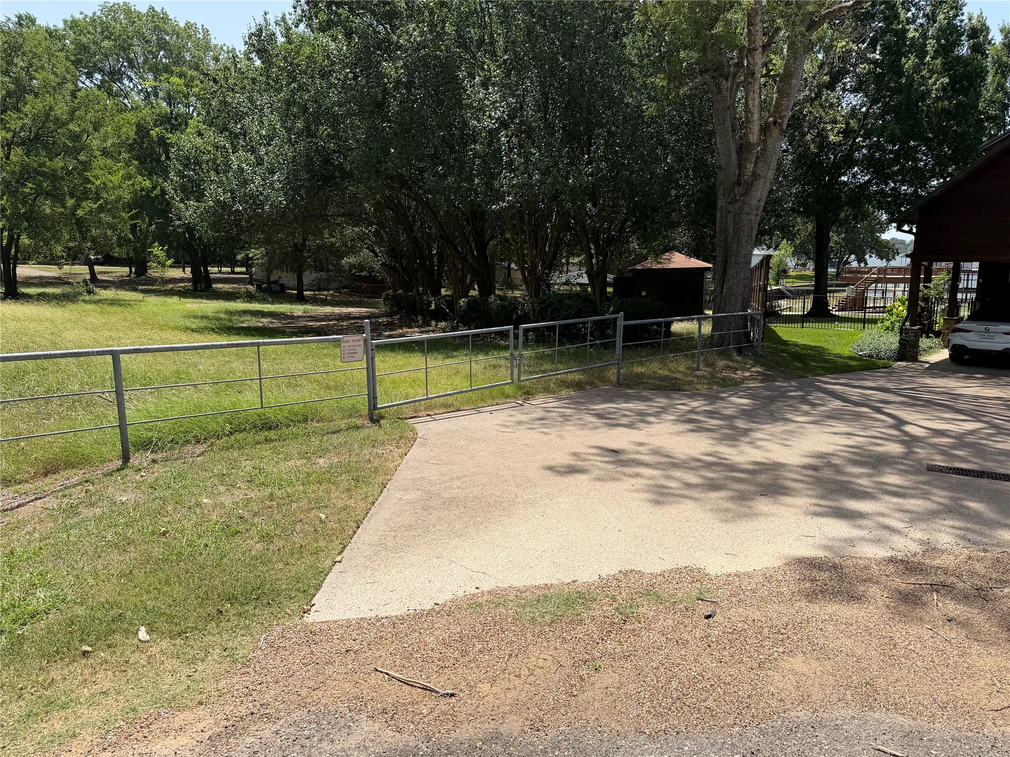 Land entry gate at the curve in Scenic Dr.  Hedges, brown building and boat dock can be seen in right half of photo remaining land is center and to the left out of picture frame.