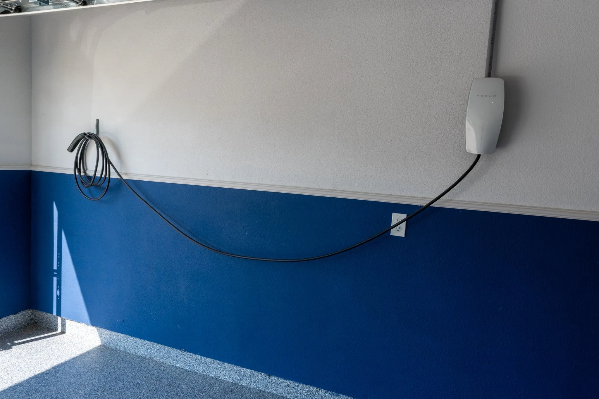 Upgraded garage featuring durable epoxy-coated floors and an installed Tesla EV charger that is included with the home, making at-home charging convenient from day one.