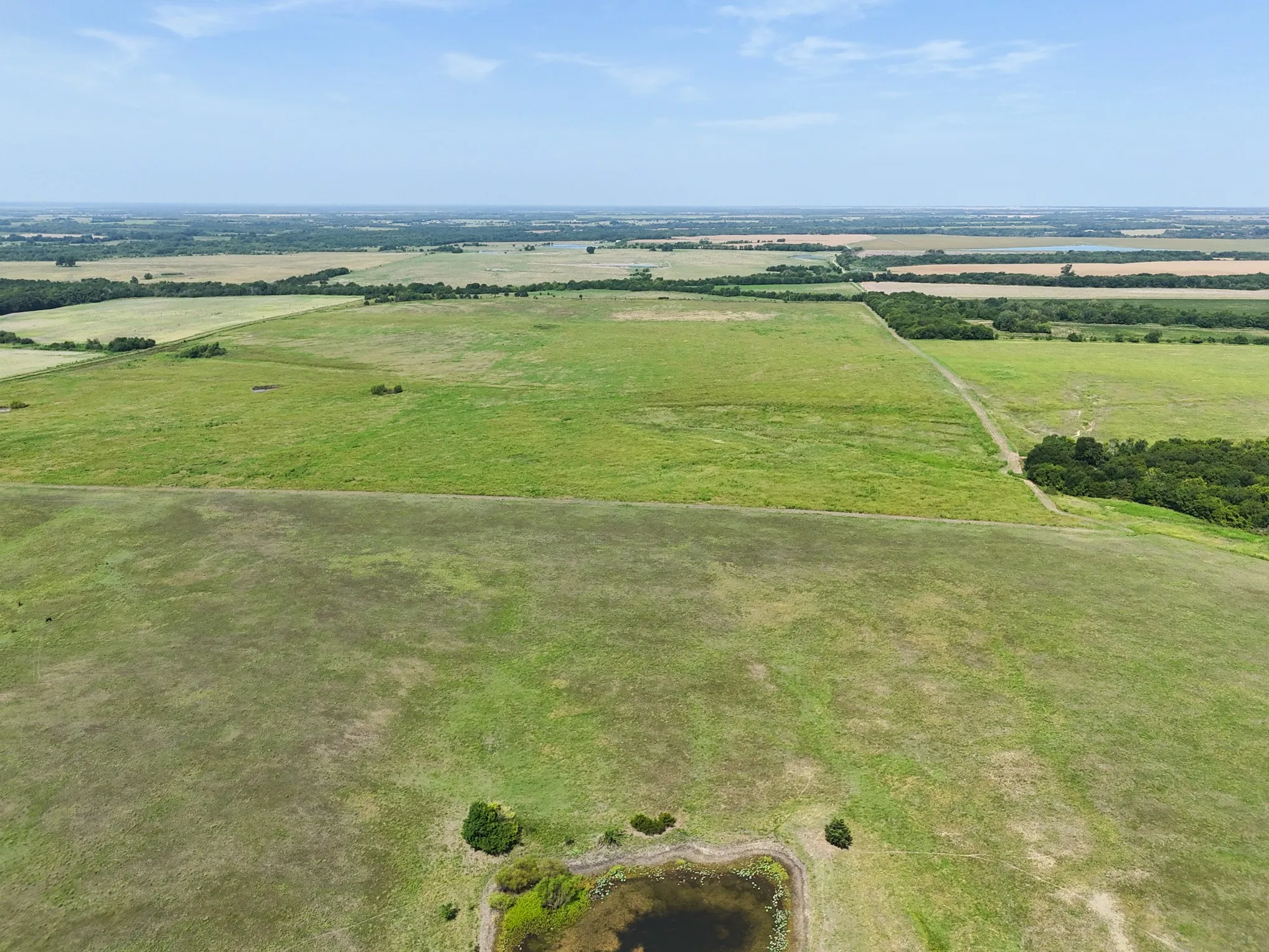 Expansive rural landscape featuring a mix of green fields and natural vegetation