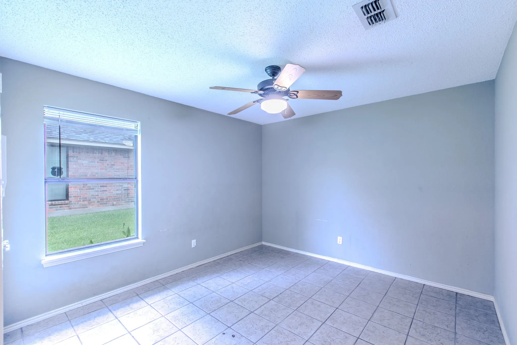 Interior room featuring neutral wall paint, tile flooring, a window with horizontal blinds, a ceiling fan with integrated lighting, and a ceiling vent