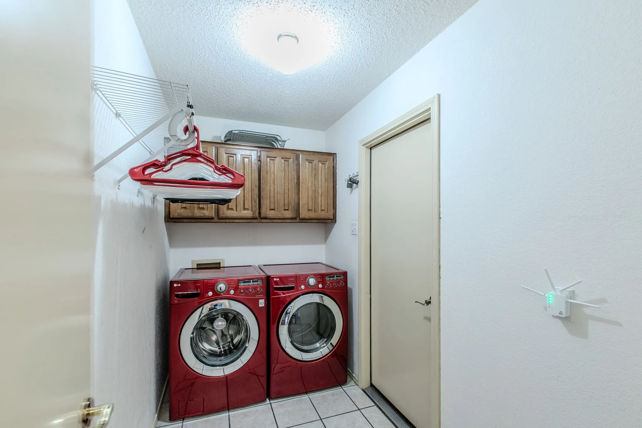 Dedicated utility space featuring overhead wood cabinetry and a ceiling-mounted light fixture