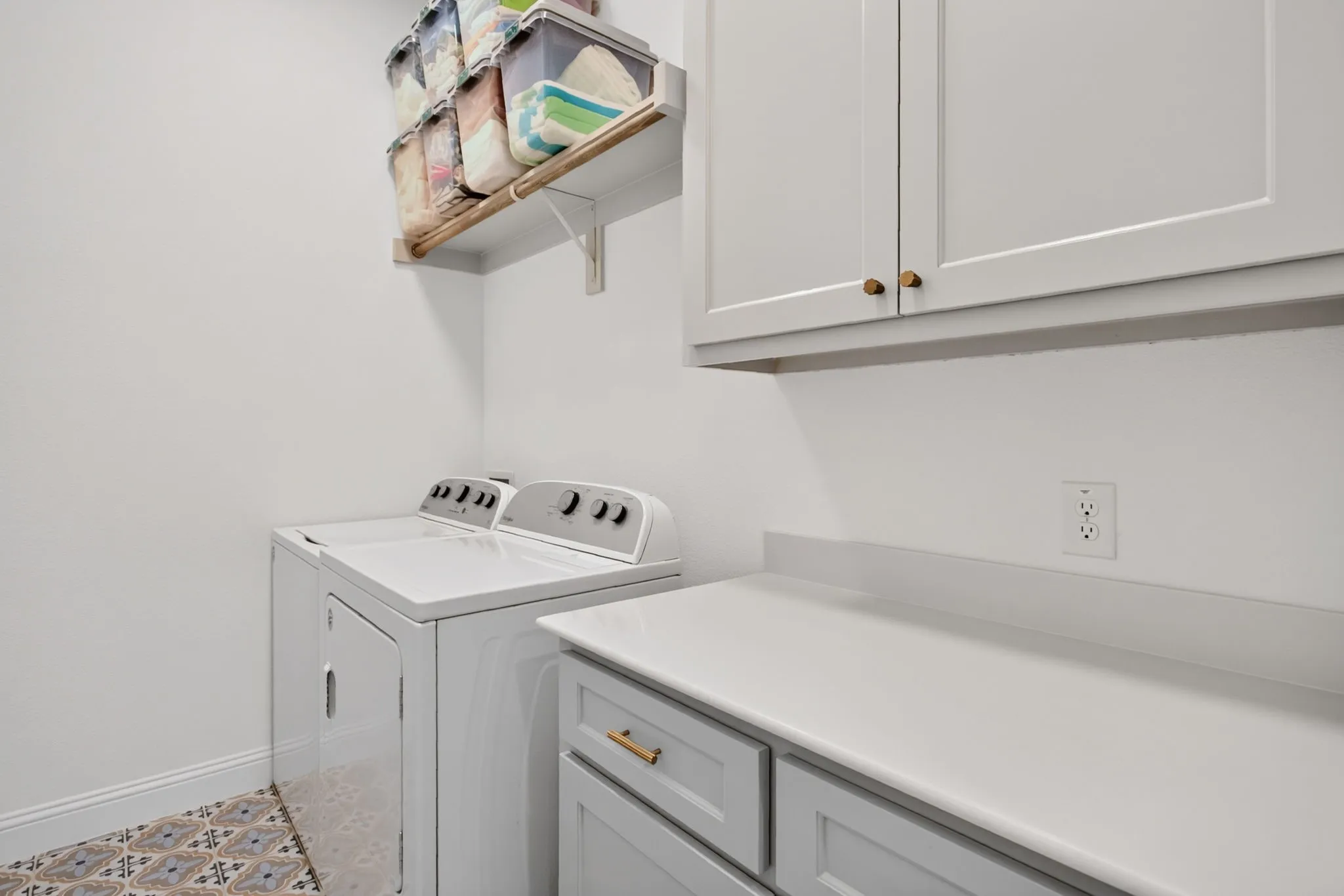 Laundry room includes drip dry rod, cabinet storage and folding counter. Deco tile floors.