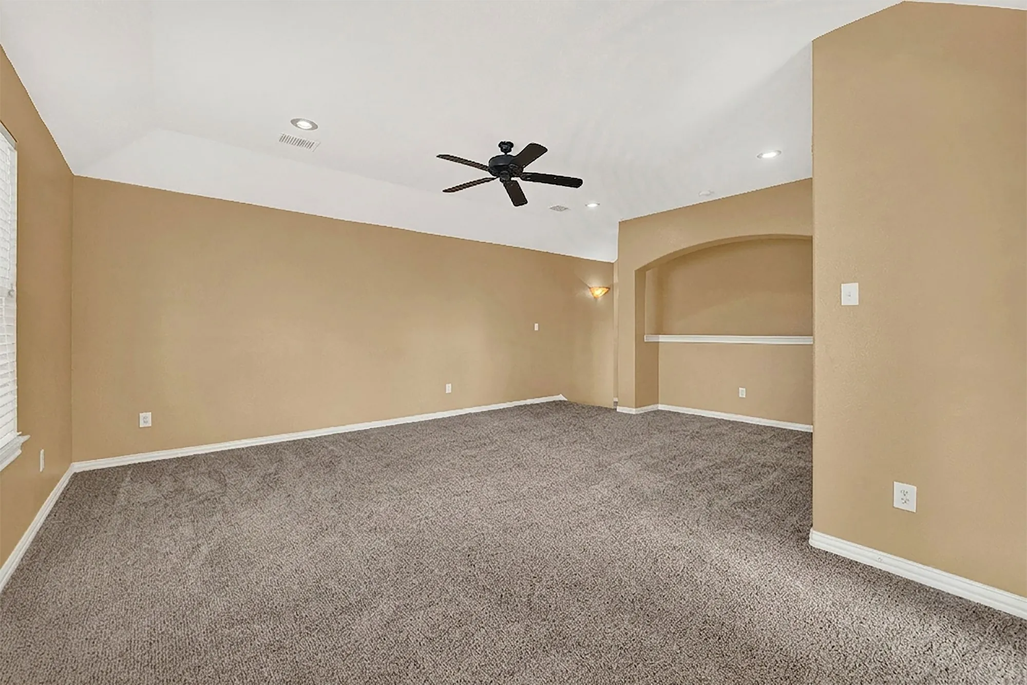 Vaulted ceiling with recessed lighting and a ceiling fan, carpet flooring, and a built-in arched niche with shelving