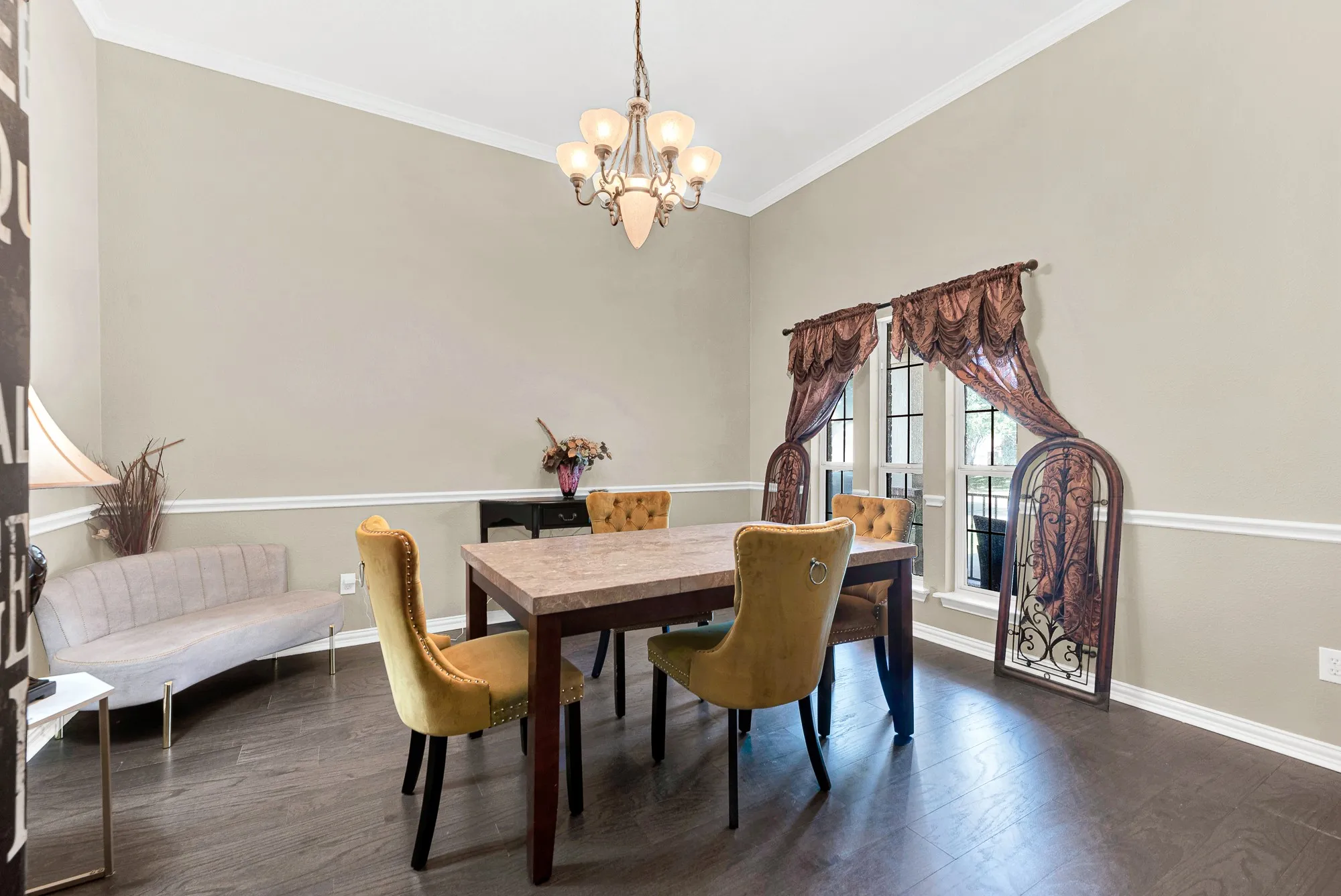 Wood-finish flooring, crown molding, chair rail molding, and a decorative chandelier