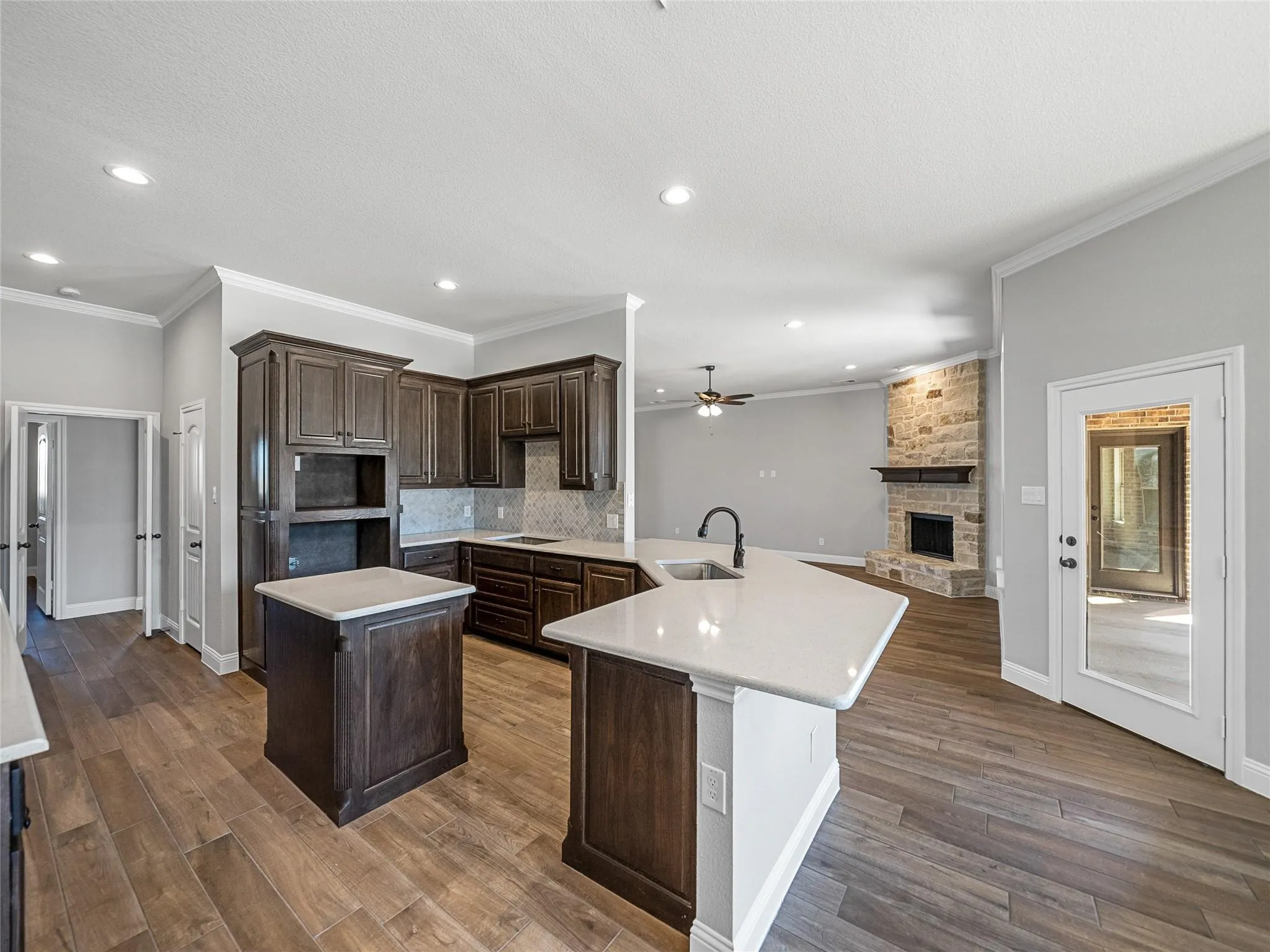 Modern kitchen featuring dark wood cabinetry, light countertops, wood-finish flooring, and recessed lighting