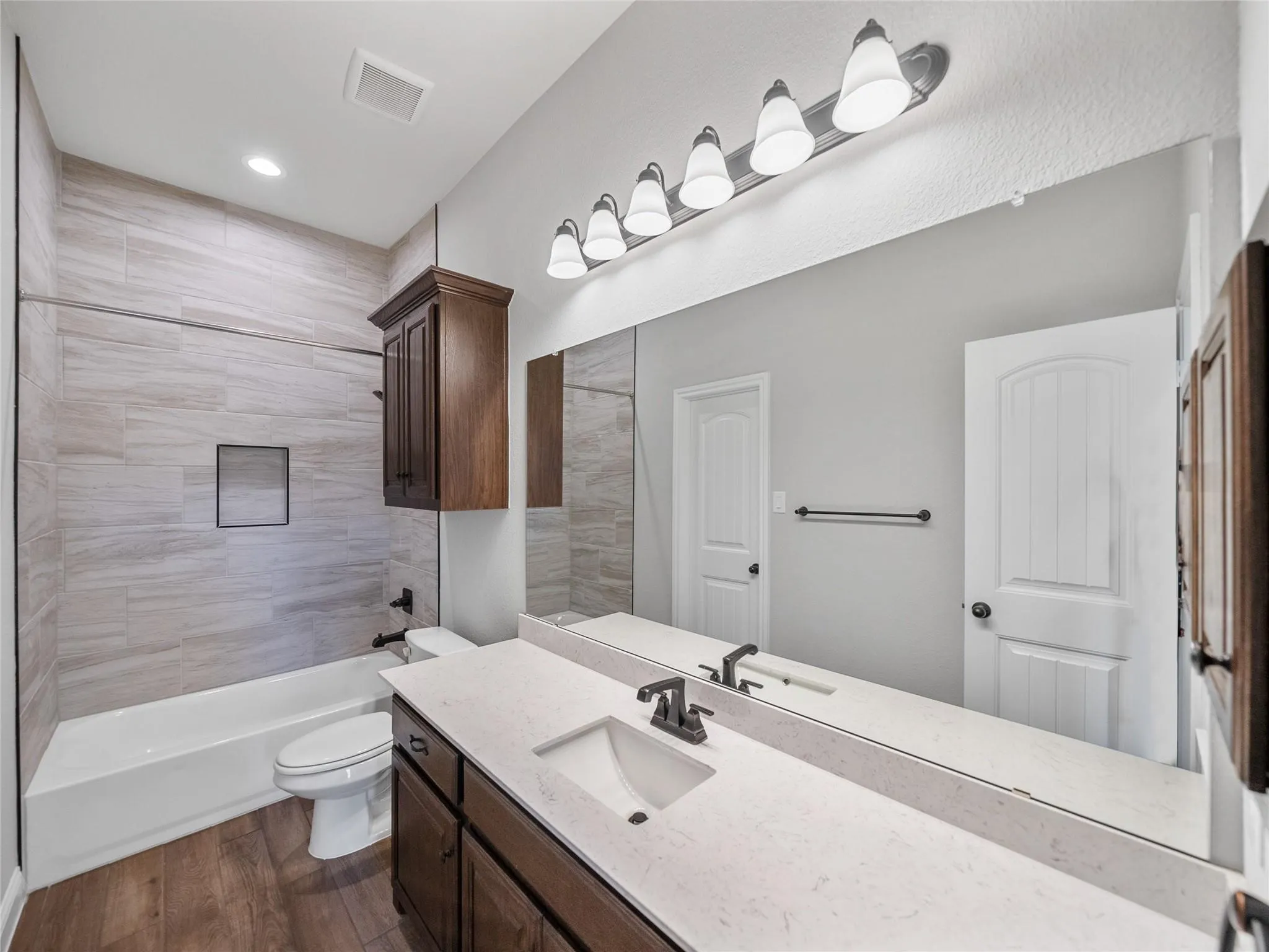 Bathroom featuring a vanity with dark wood-finish cabinetry, a light-colored countertop, and a rectangular undermount sink with a matte black faucet