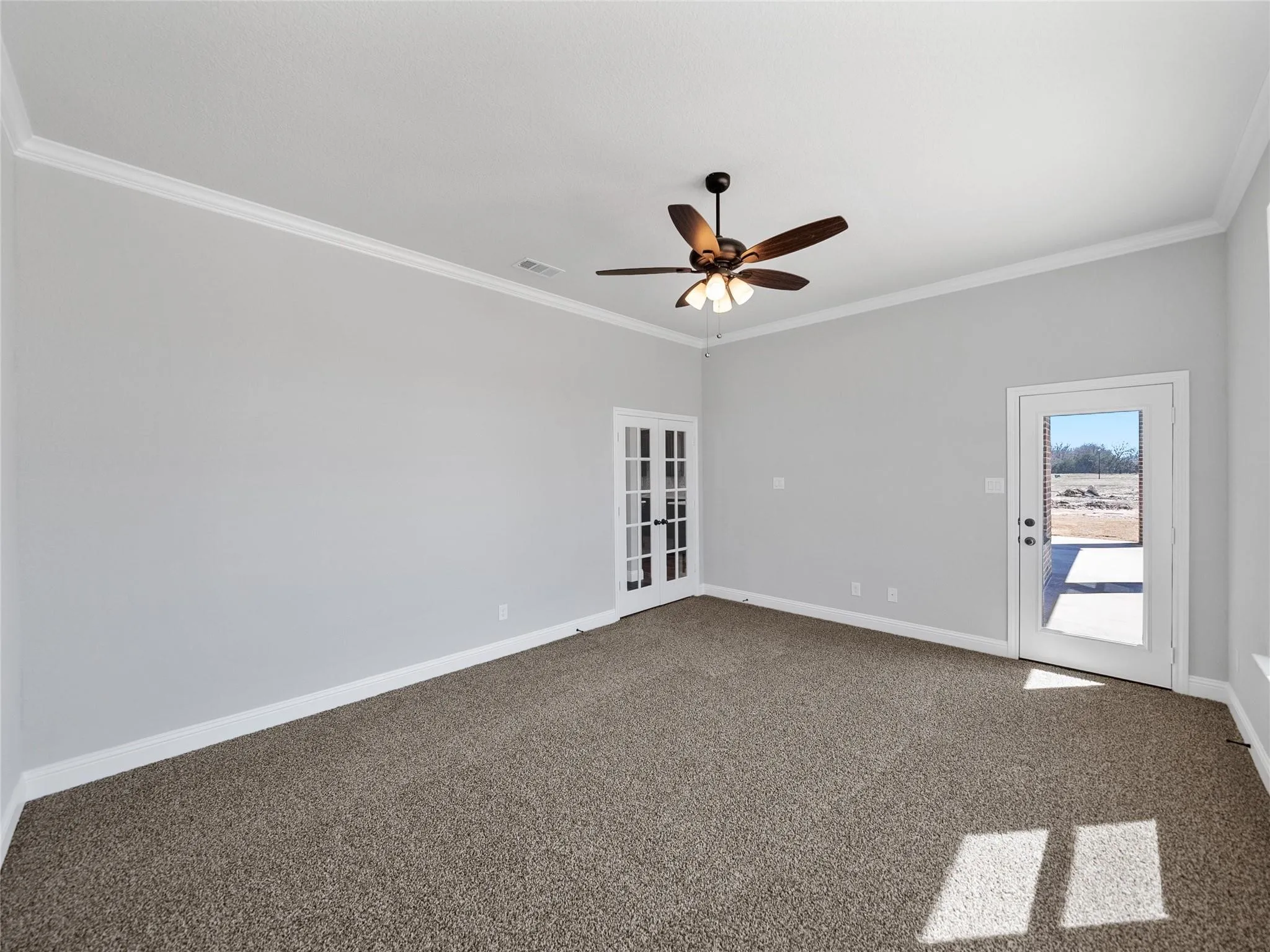 Spacious room featuring vaulted ceilings, crown molding, a ceiling fan, and carpeted flooring