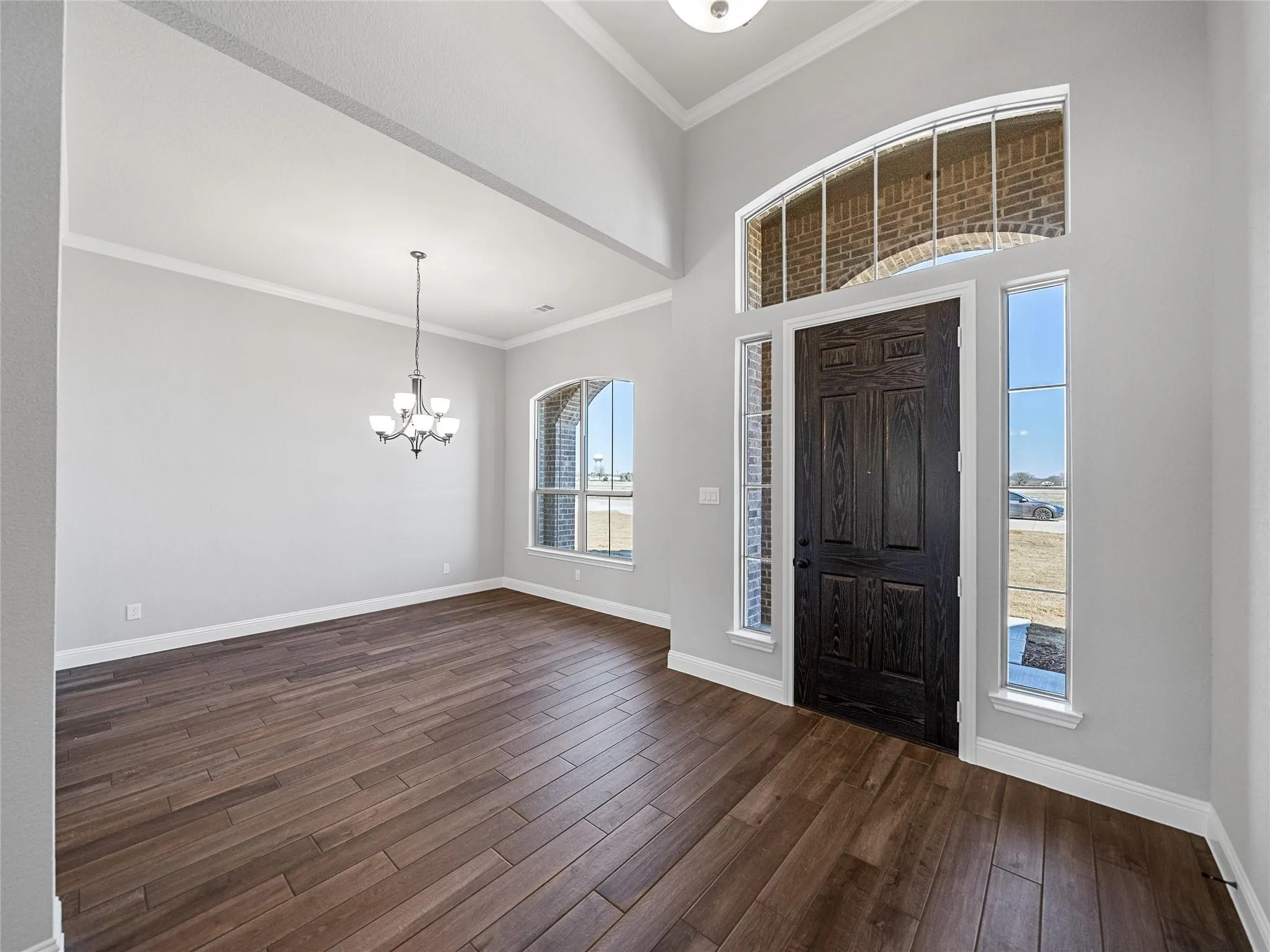Grand entryway featuring a dark wood-finish door with sidelights and an arched transom window
