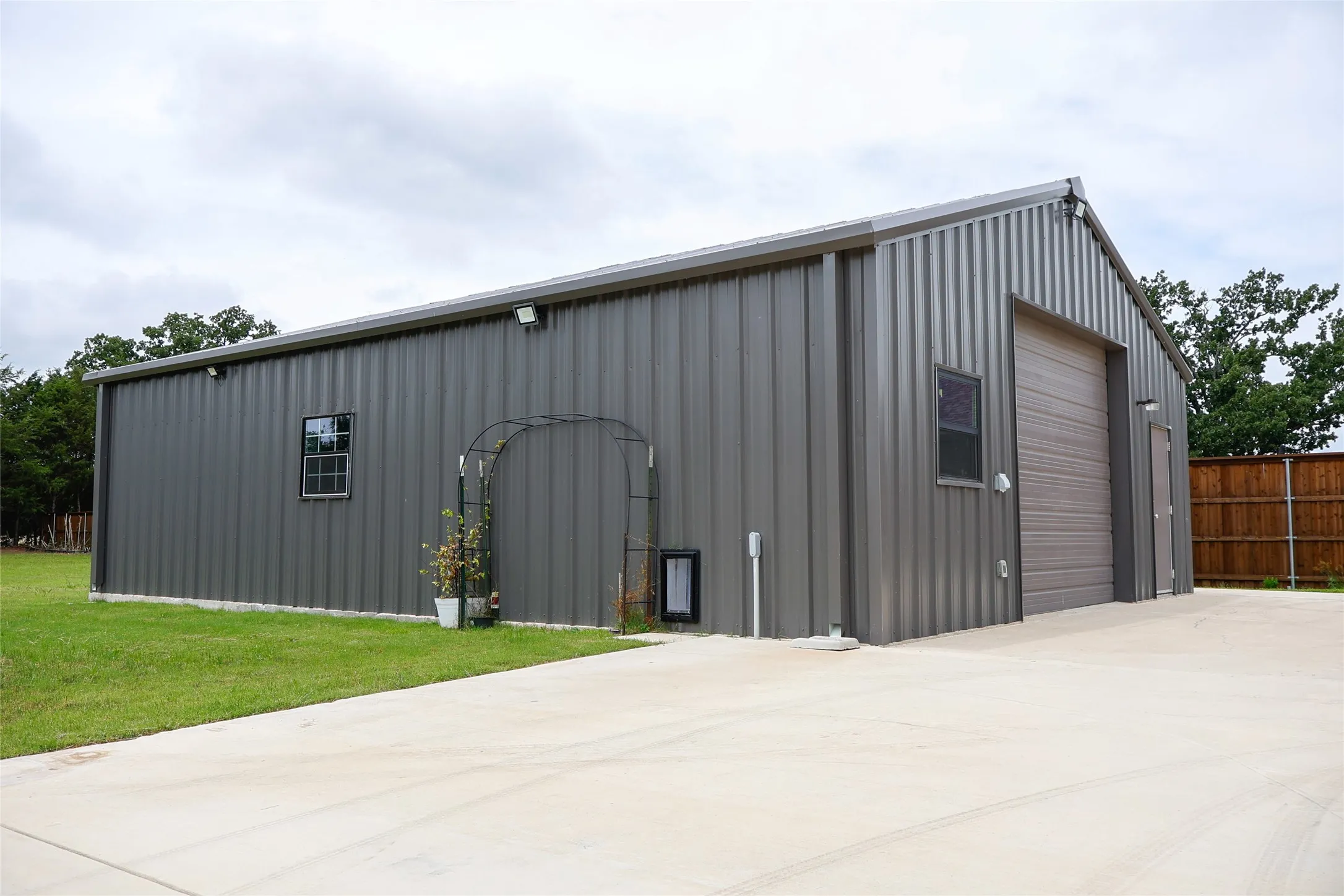 Spacious metal building featuring a pitched roofline, corrugated siding, multiple windows, and two distinct roll-up garage doors