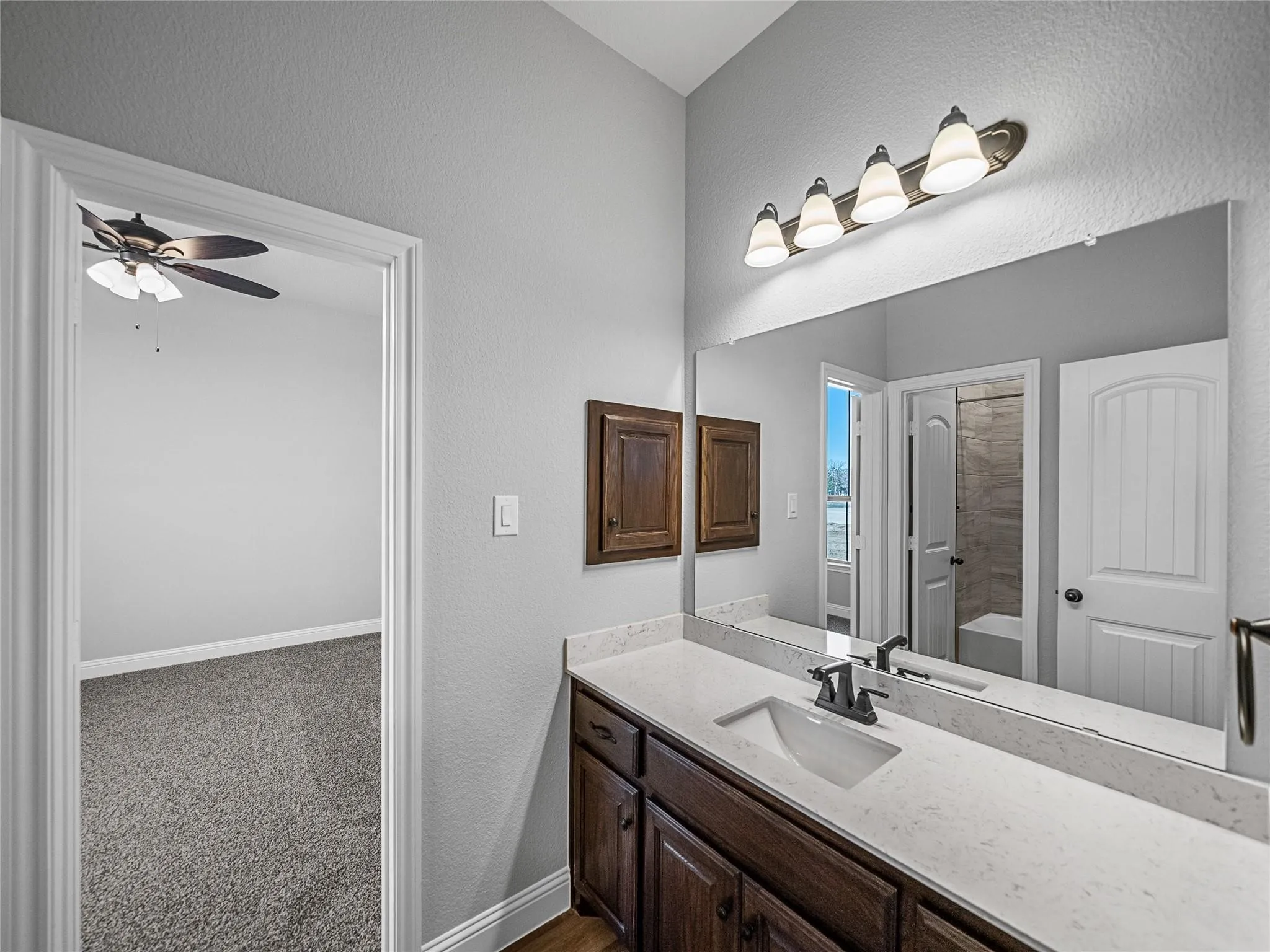 Bathroom vanity featuring a quartz countertop, integrated rectangular sink, and dark wood-finish cabinetry
