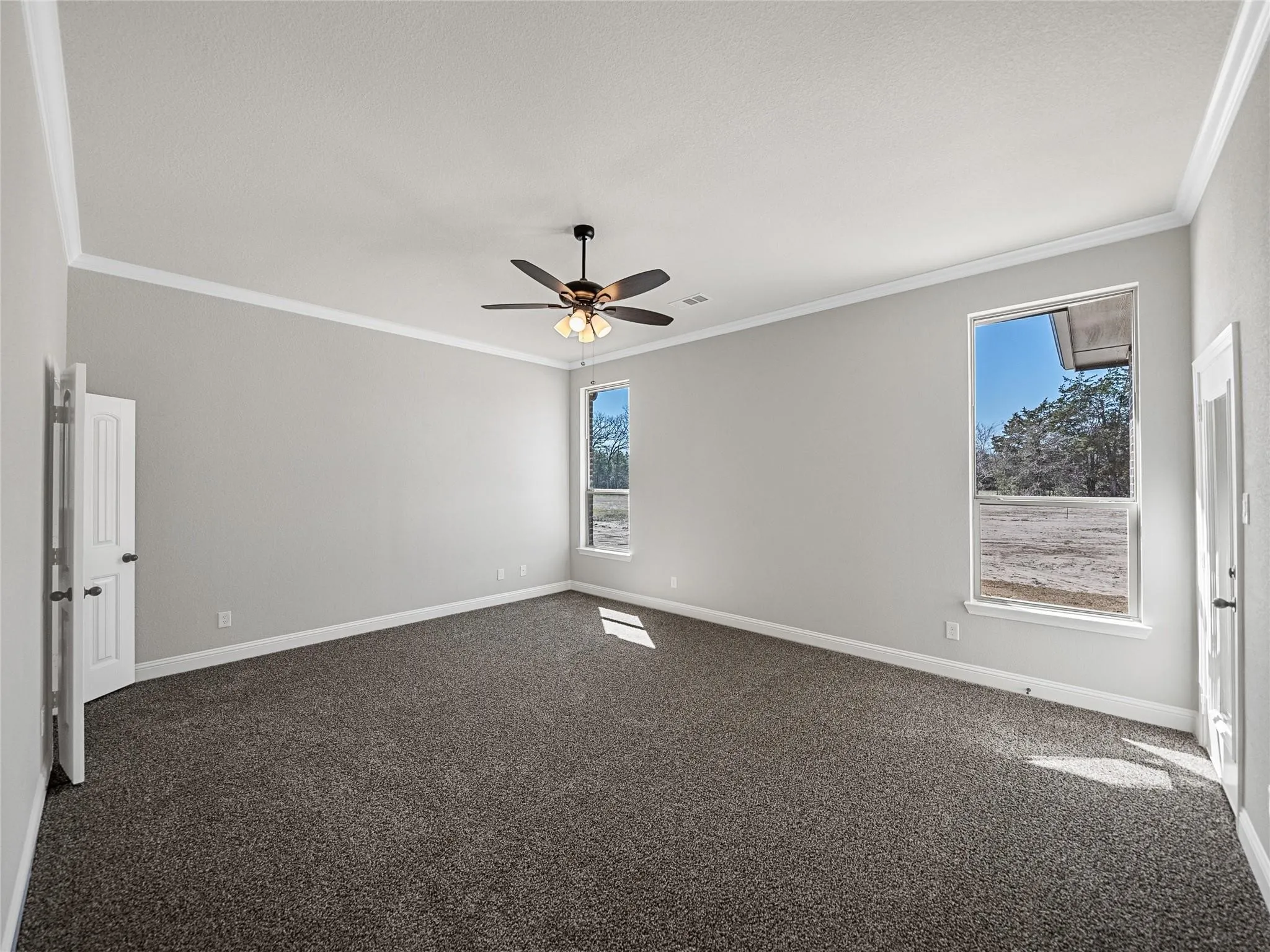 Spacious room featuring neutral carpeting, light-toned walls, and white crown molding