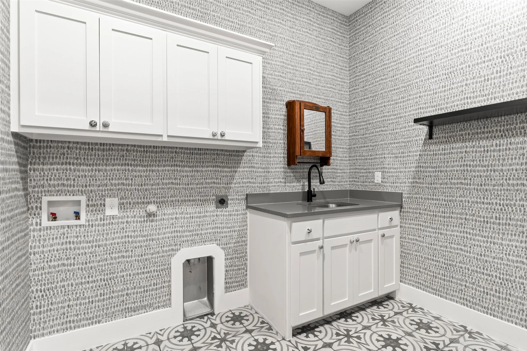 Premium wallpaper and decorative tile elevate the space. The utility sink makes quick cleanup tasks and soaking effortless.