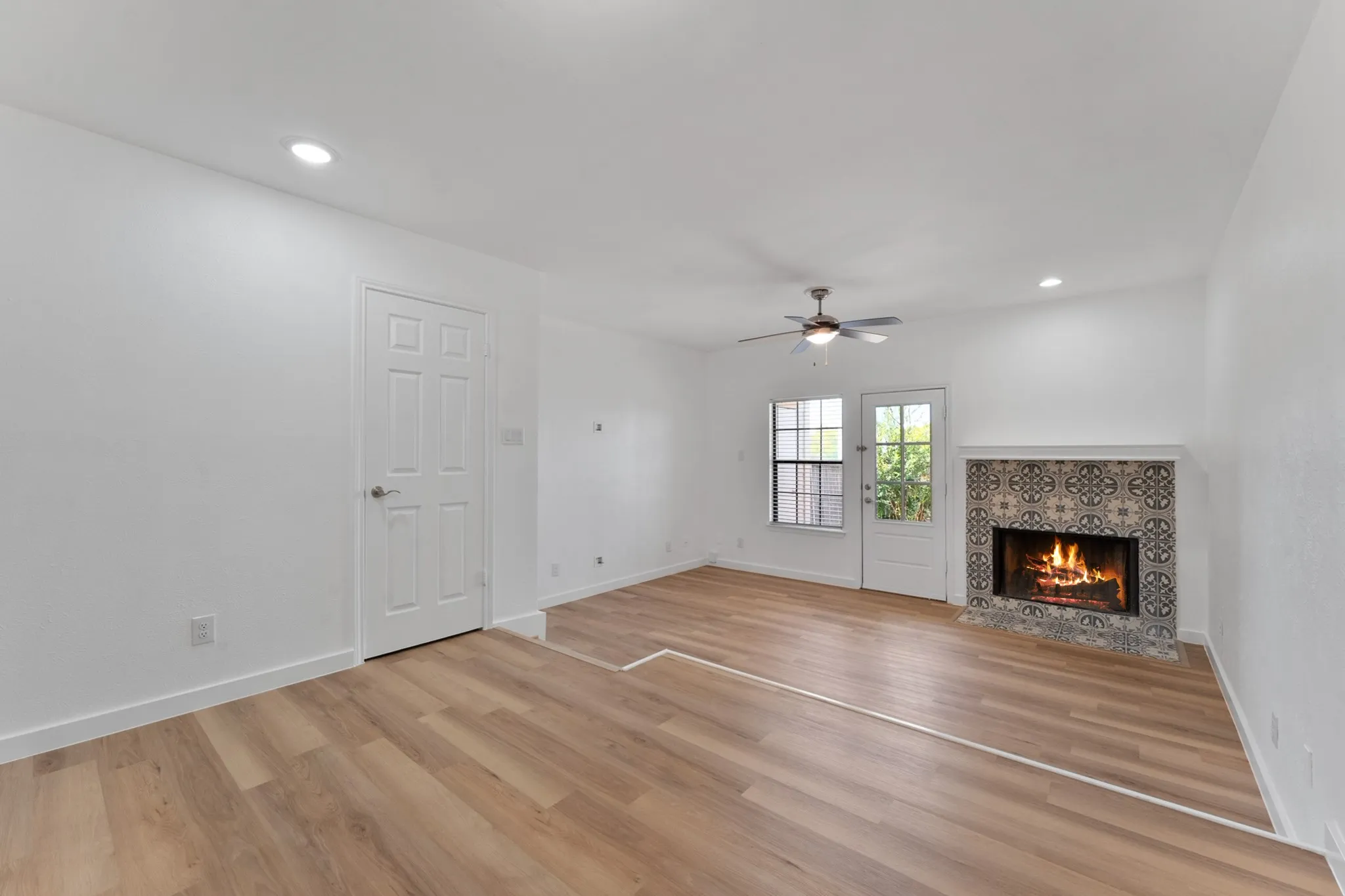 Living area featuring wood-finish flooring, a decorative fireplace with patterned tile surround, recessed lighting, and a ceiling fan