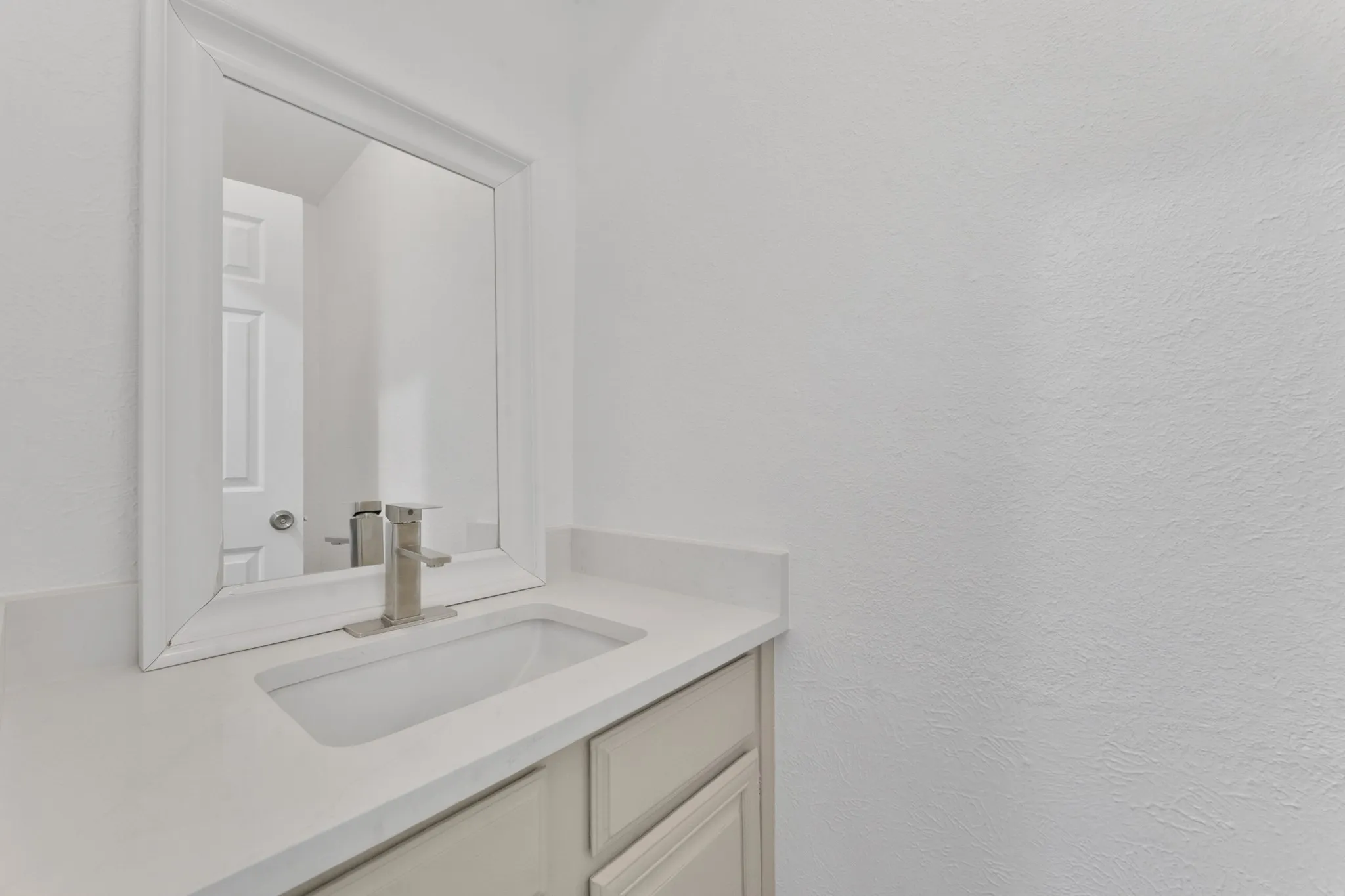 Contemporary vanity featuring a rectangular undermount sink, a sleek brushed nickel faucet, and a white countertop