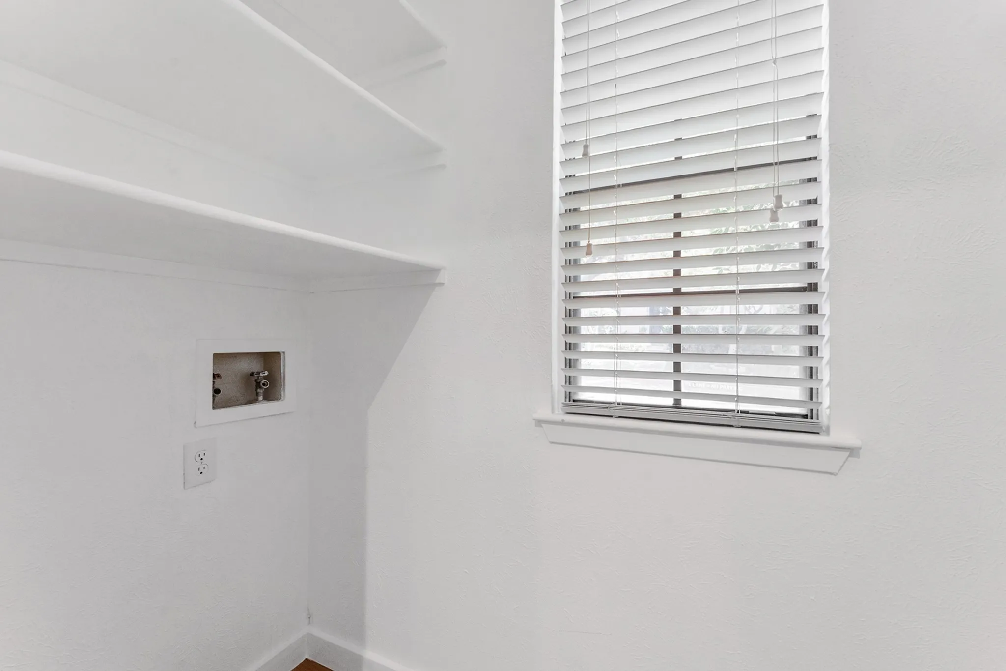 Dedicated laundry area featuring built-in shelving, a wall outlet, and plumbing hookups