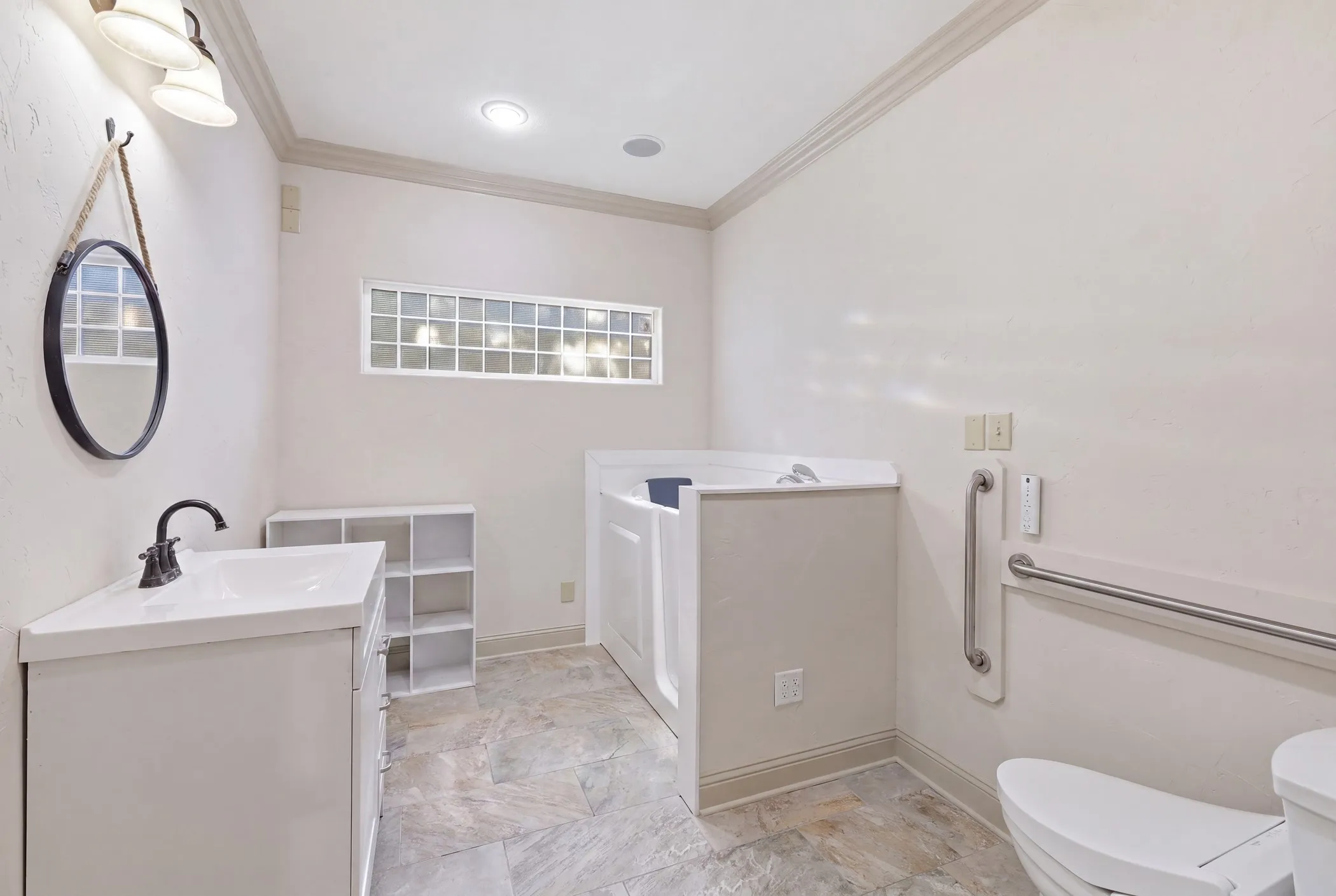 Bathroom featuring a vanity with an integrated sink, a walk-in tub, and a toilet