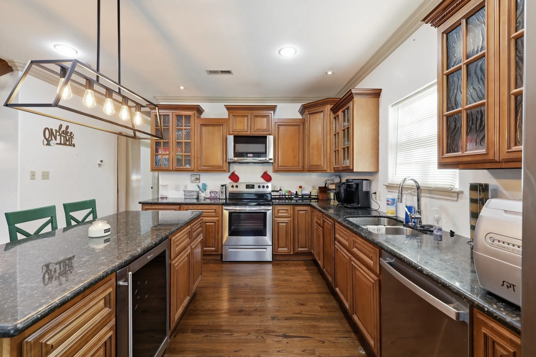 Kitchen featuring wood-finish flooring, granite countertops, and light wood cabinetry