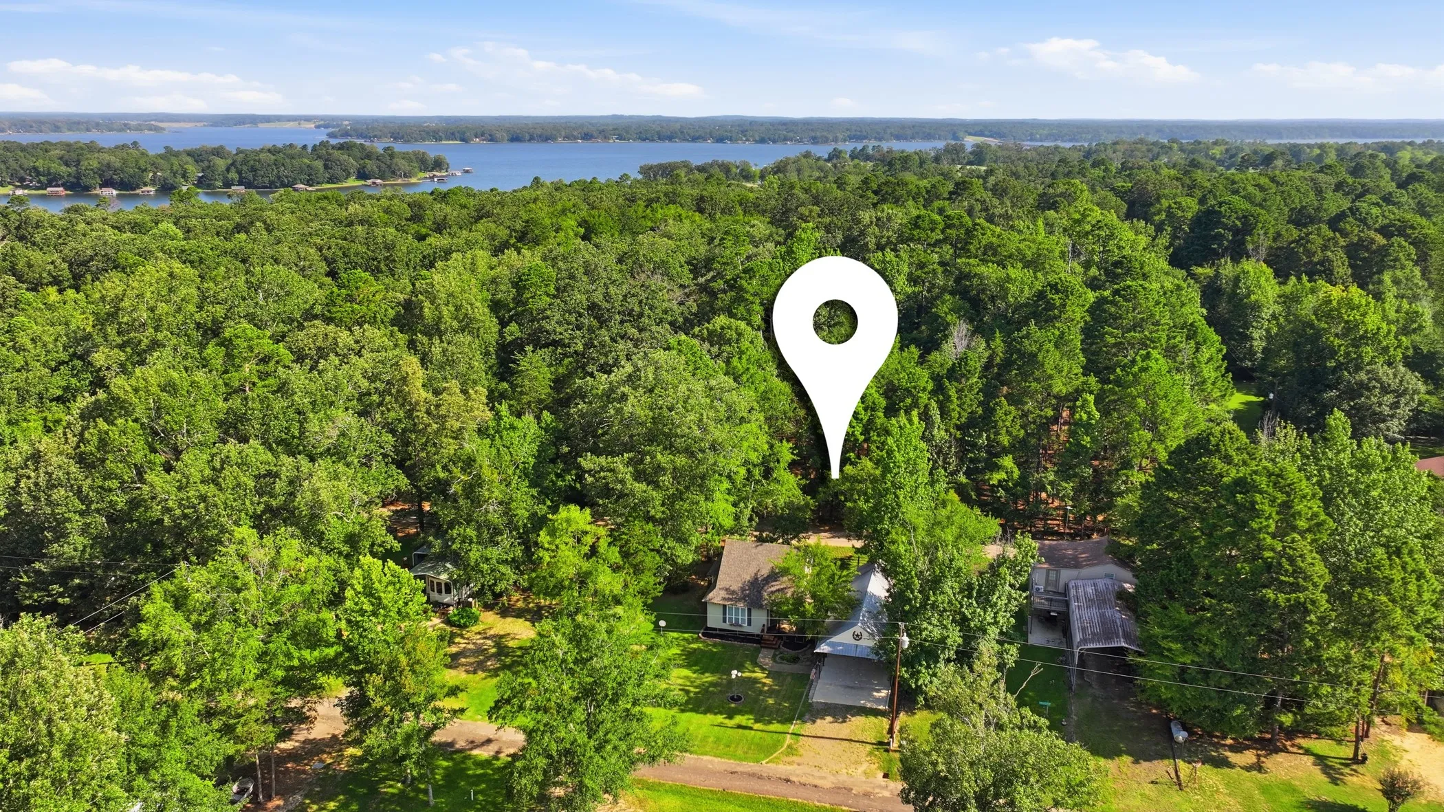 Wooded property with lake proximity, featuring a single-story residence and mature tree canopy