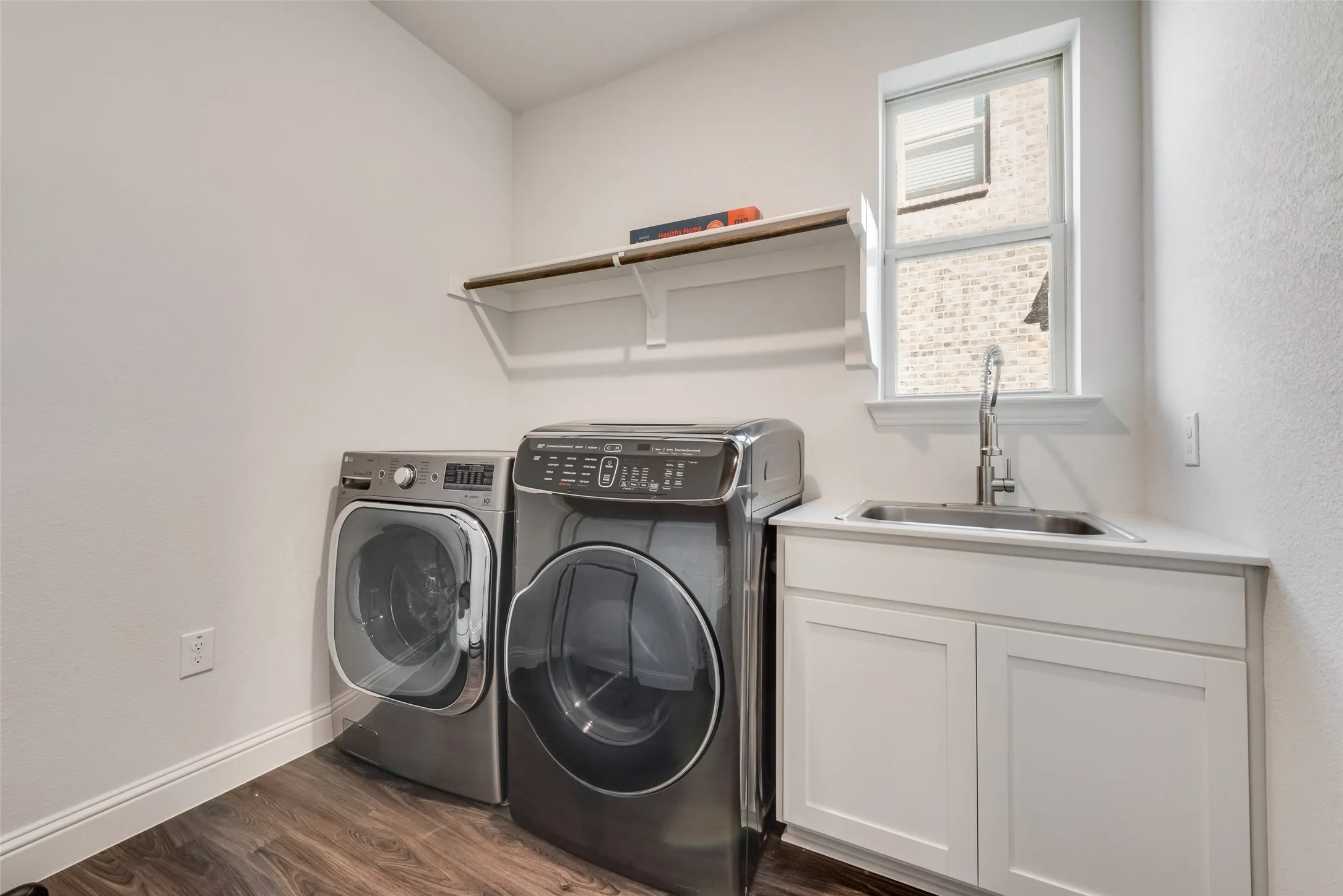 Dedicated utility space featuring wood-finish flooring and a window for natural light