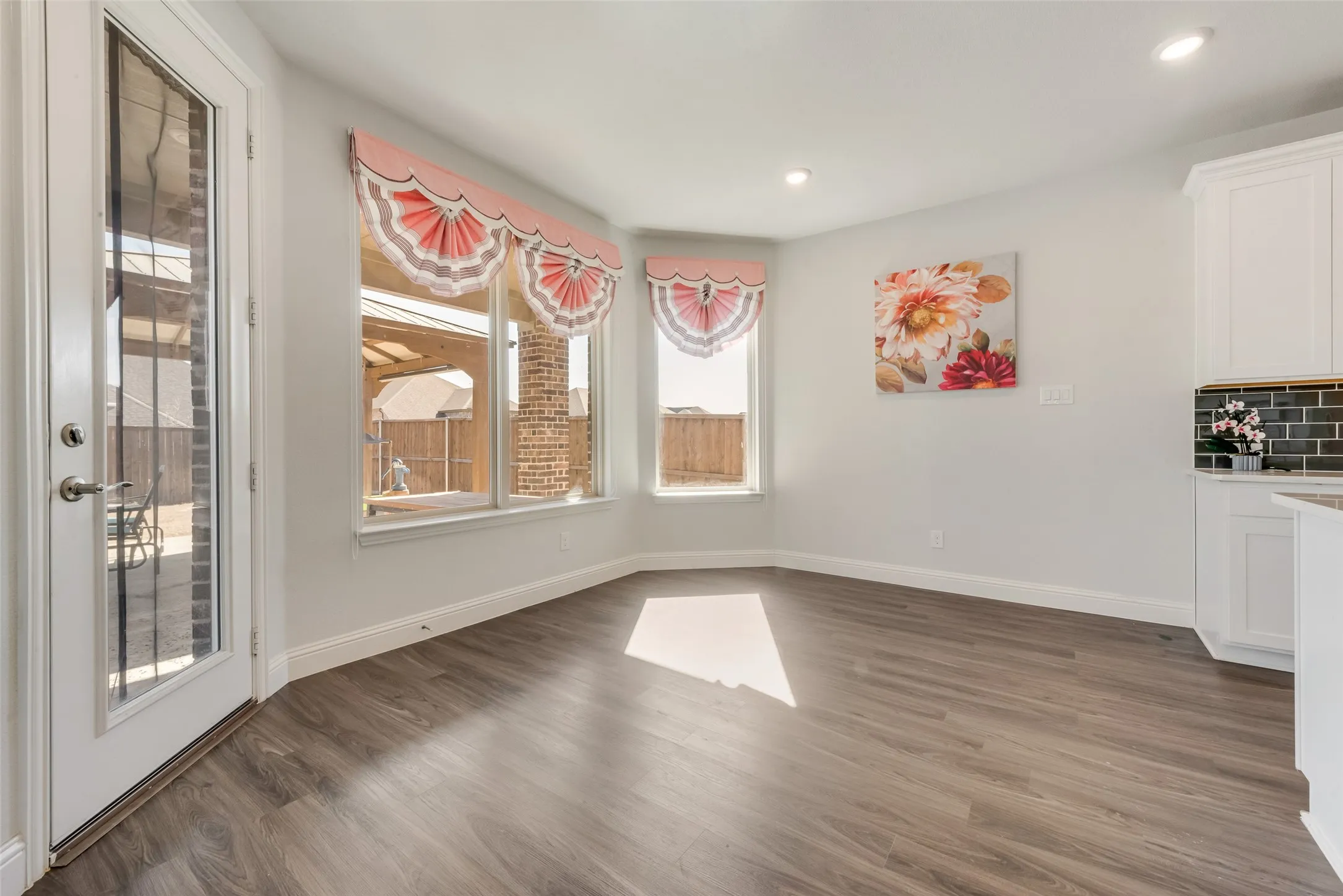 Spacious room featuring wood-finish flooring, recessed lighting, and a white paneled door with clear glass