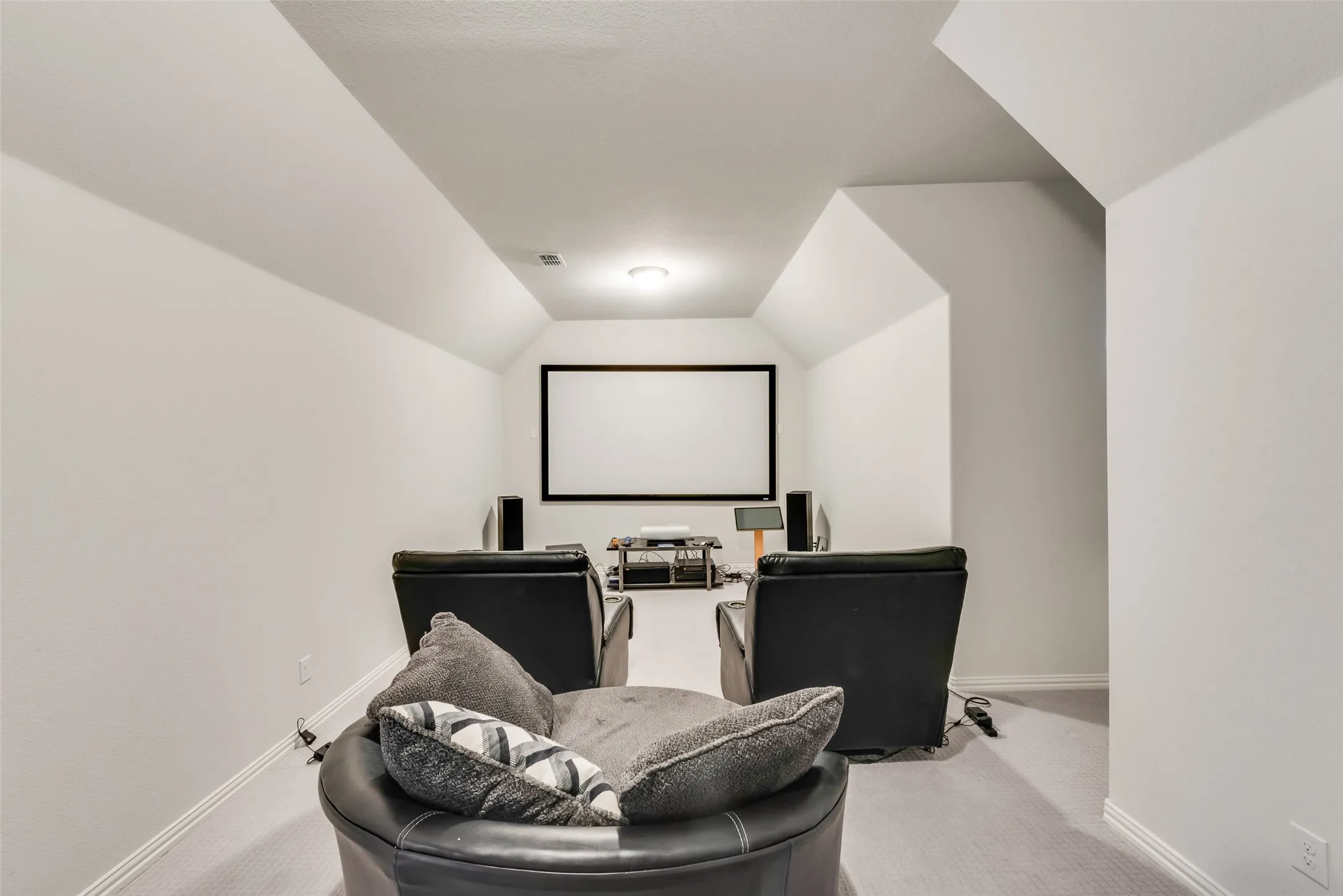 Dedicated media room featuring a large projection screen, recessed ceiling light, wall-to-wall carpeting, and sloped ceilings