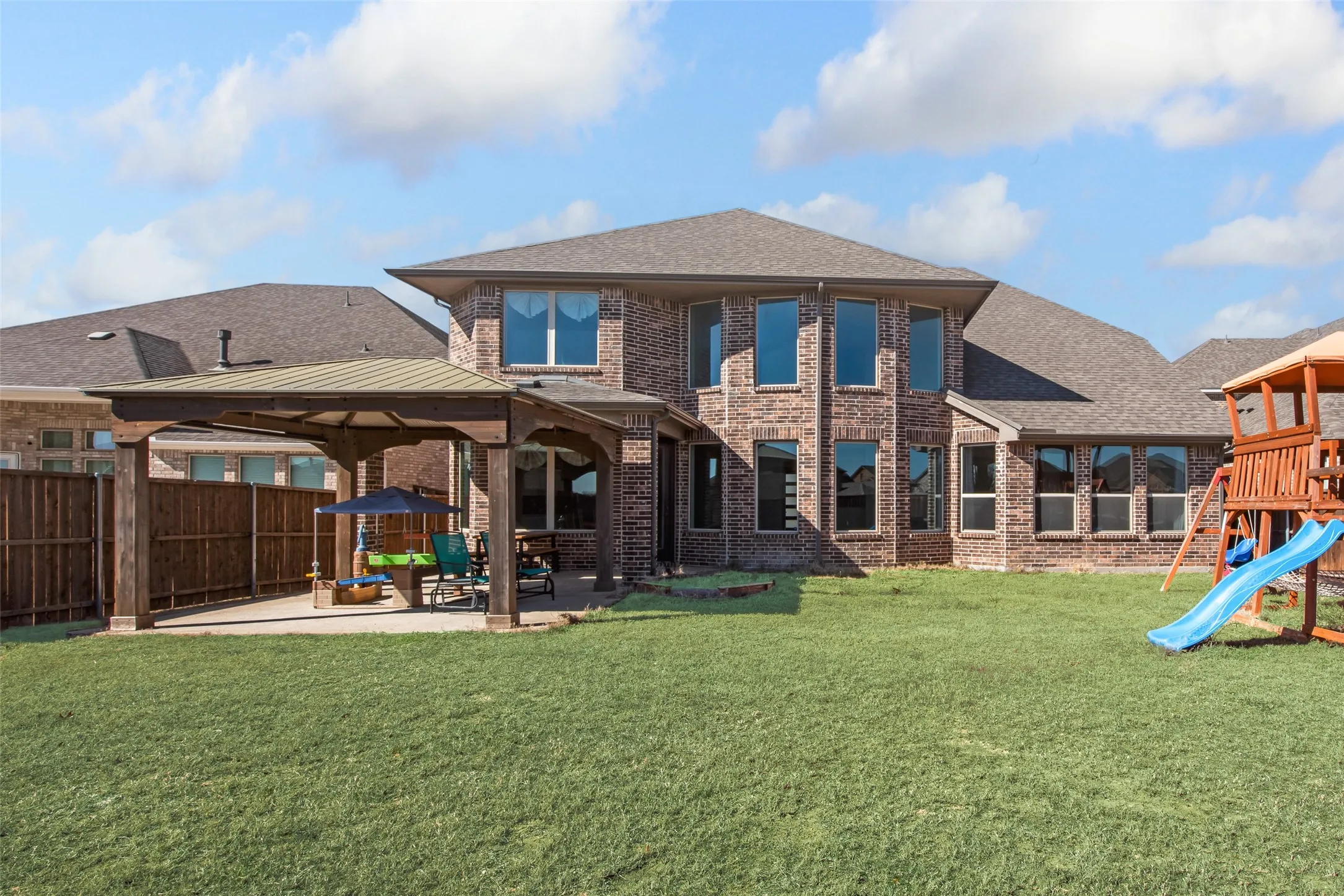 Spacious backyard featuring a covered patio with a metal roof and concrete flooring