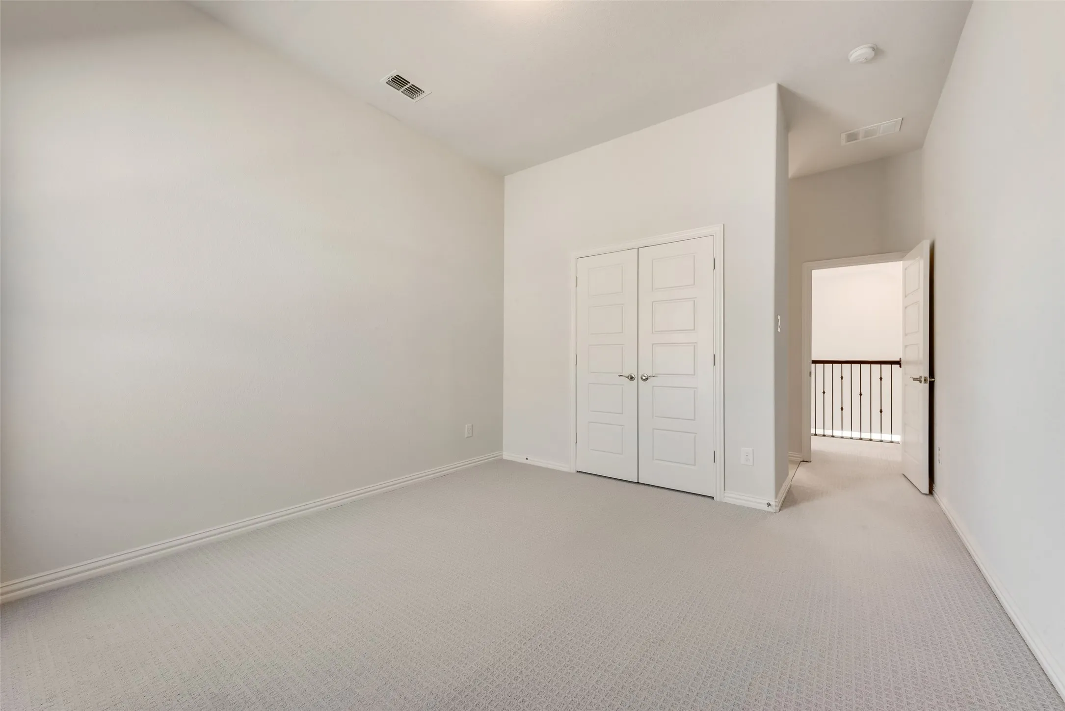 Carpeted room featuring a double-door closet with contemporary paneling and chrome hardware
