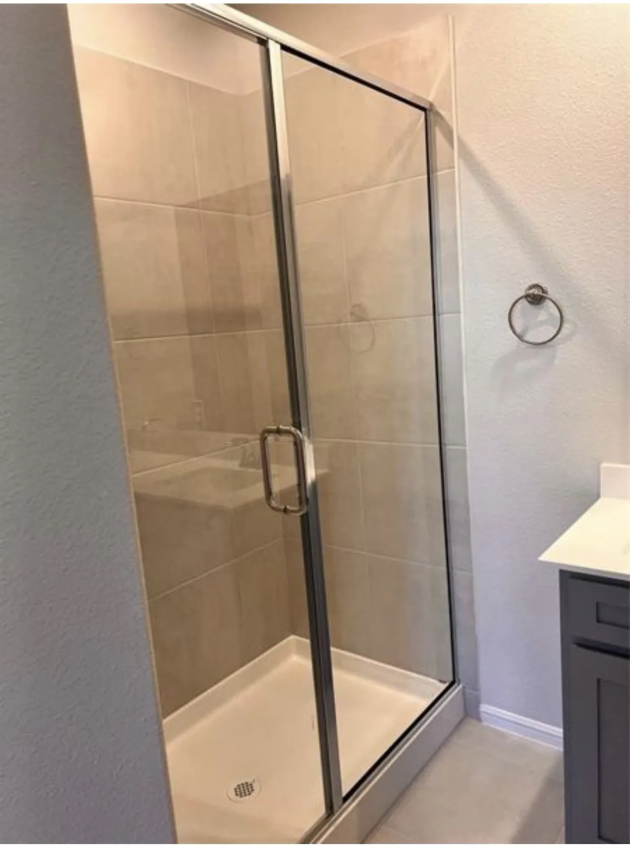 Glass-enclosed shower with a tiled surround and a white shower pan