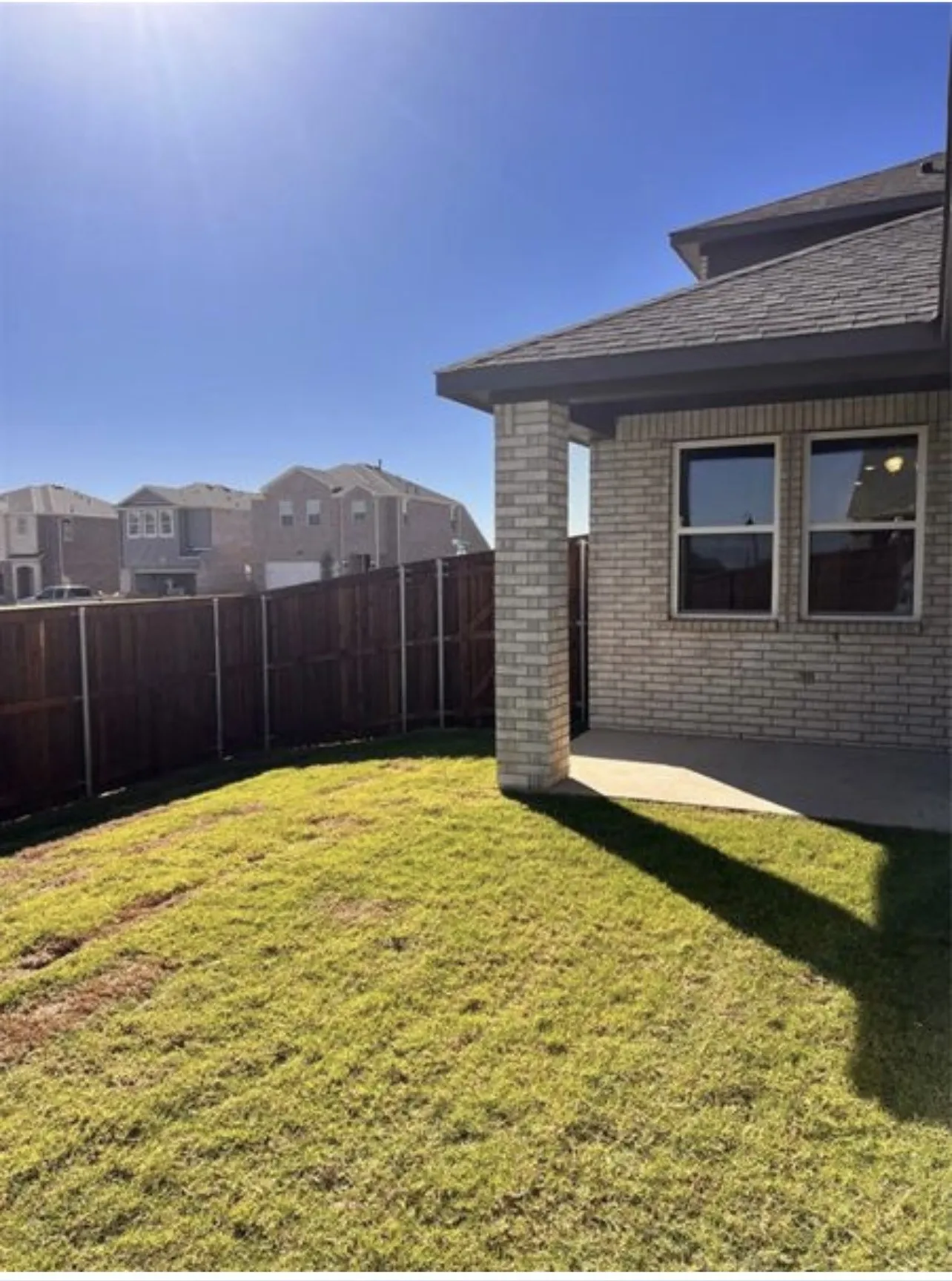 Expansive backyard featuring a manicured lawn, a full wood privacy fence, and an integrated covered patio