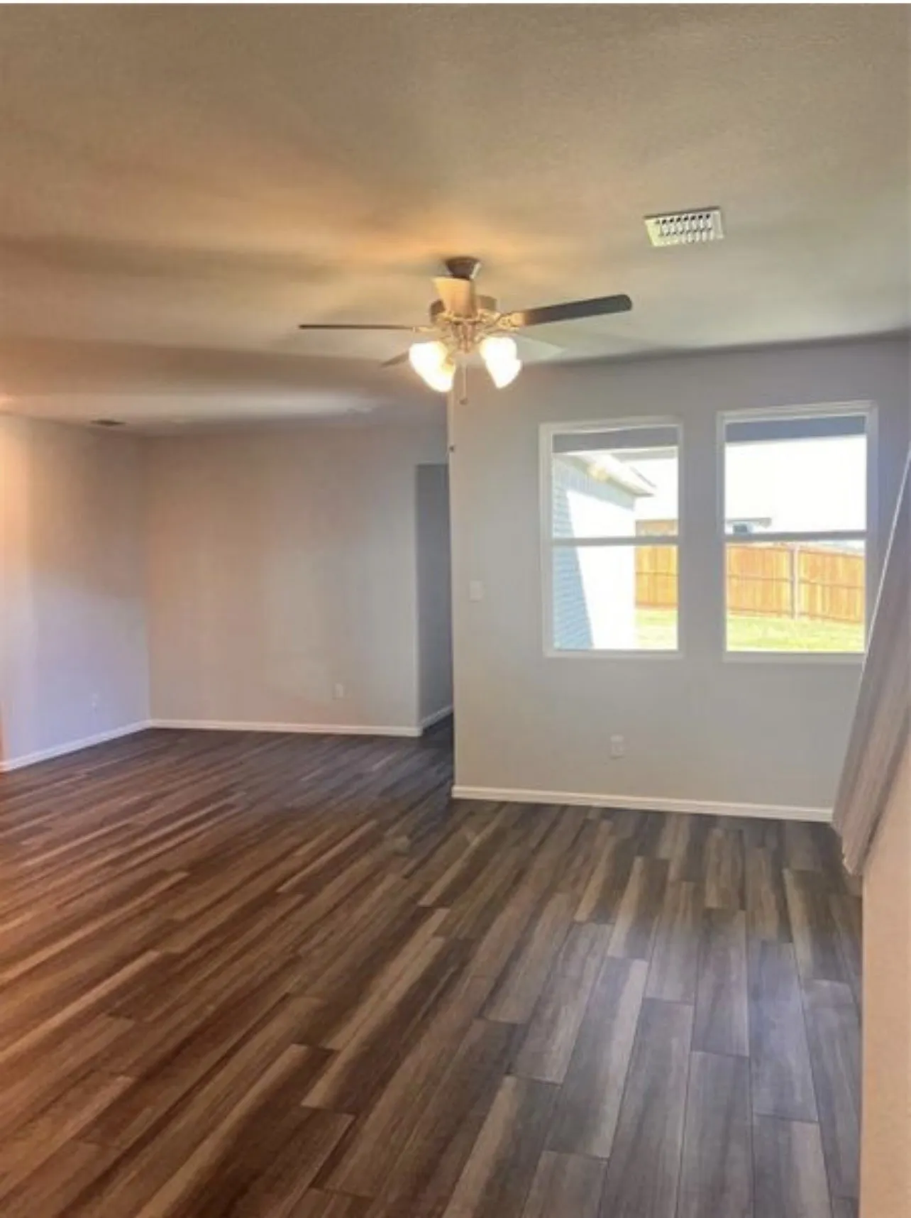 Spacious interior featuring wood-finish flooring, light grey wall paint, and white baseboards