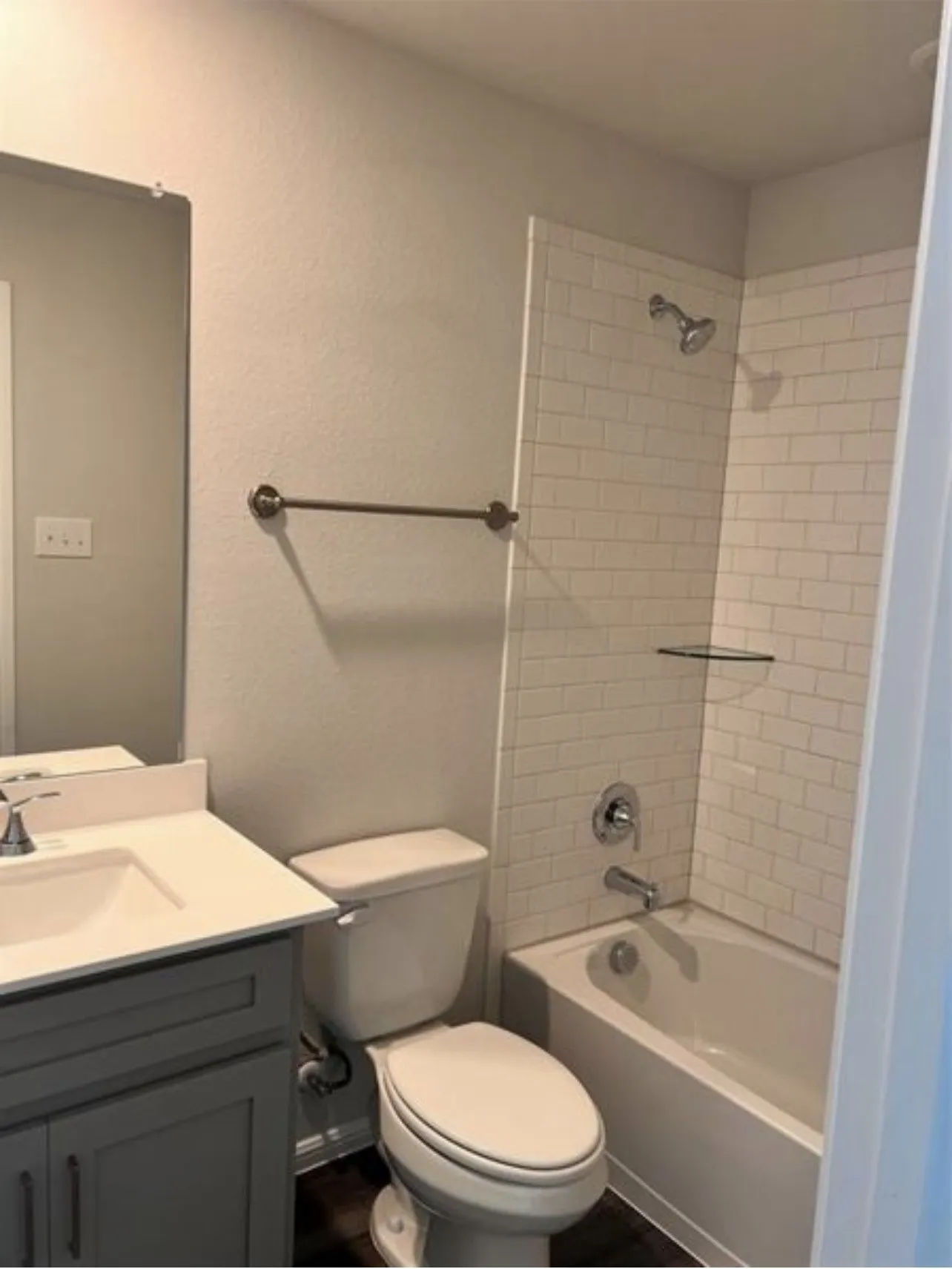 Bathroom featuring a vanity with a white countertop and undermount sink, a toilet, and a bathtub with white subway tile surround