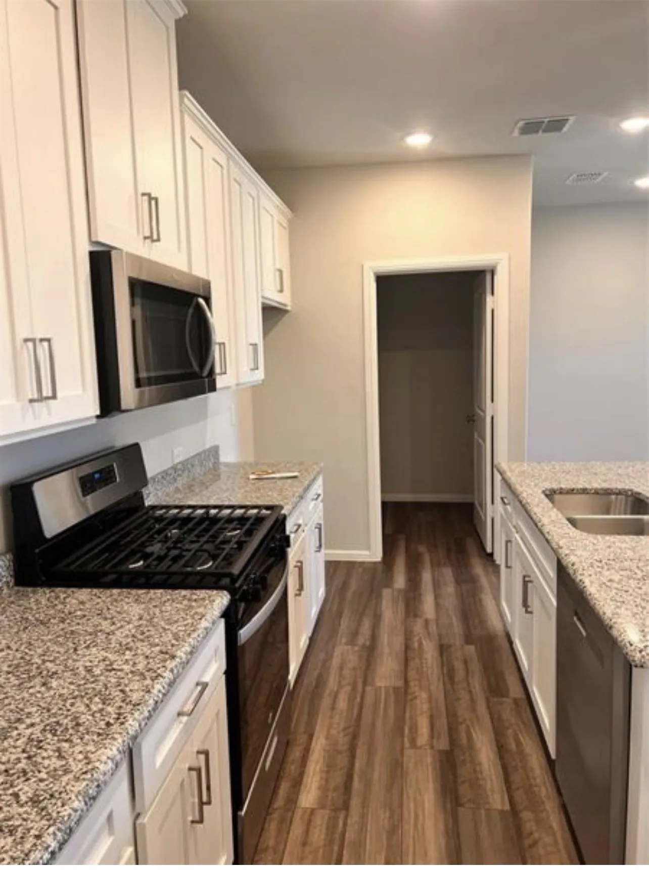 Kitchen featuring wood-finish flooring, white cabinetry with brushed nickel hardware, and granite countertops